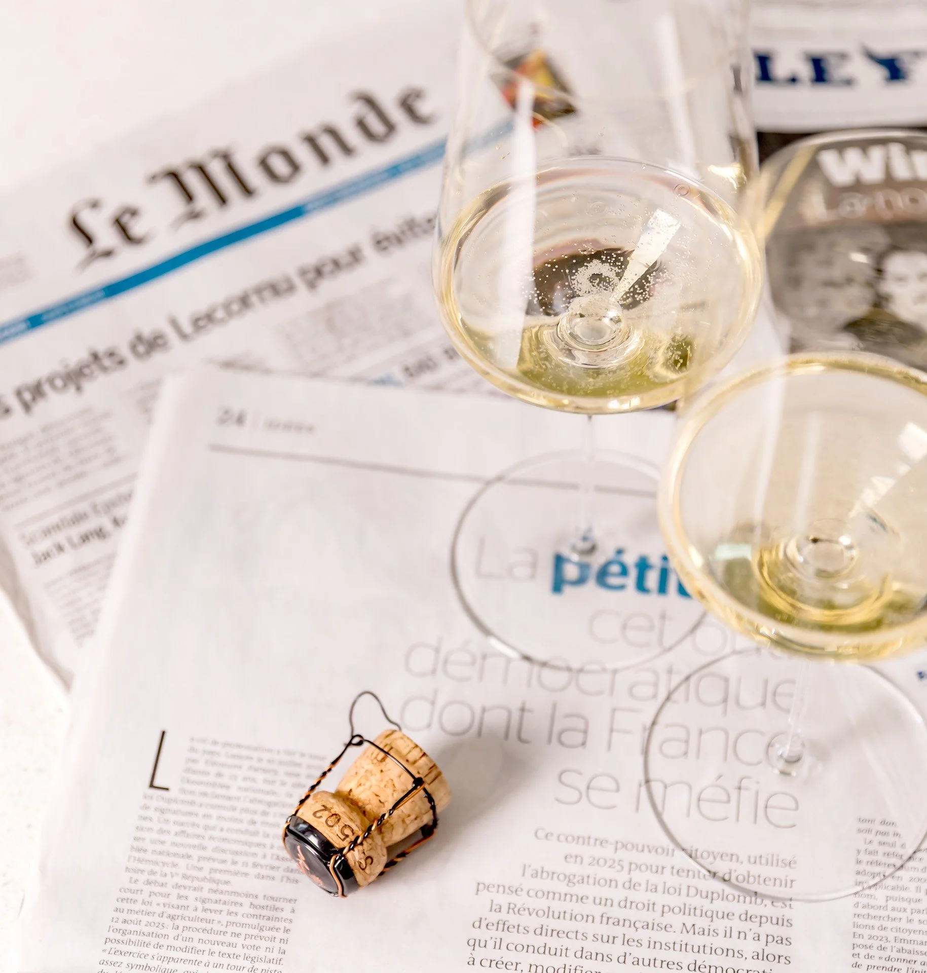Zwei Champagnergläser und ein Champagnerkorken auf französischen Tageszeitungen