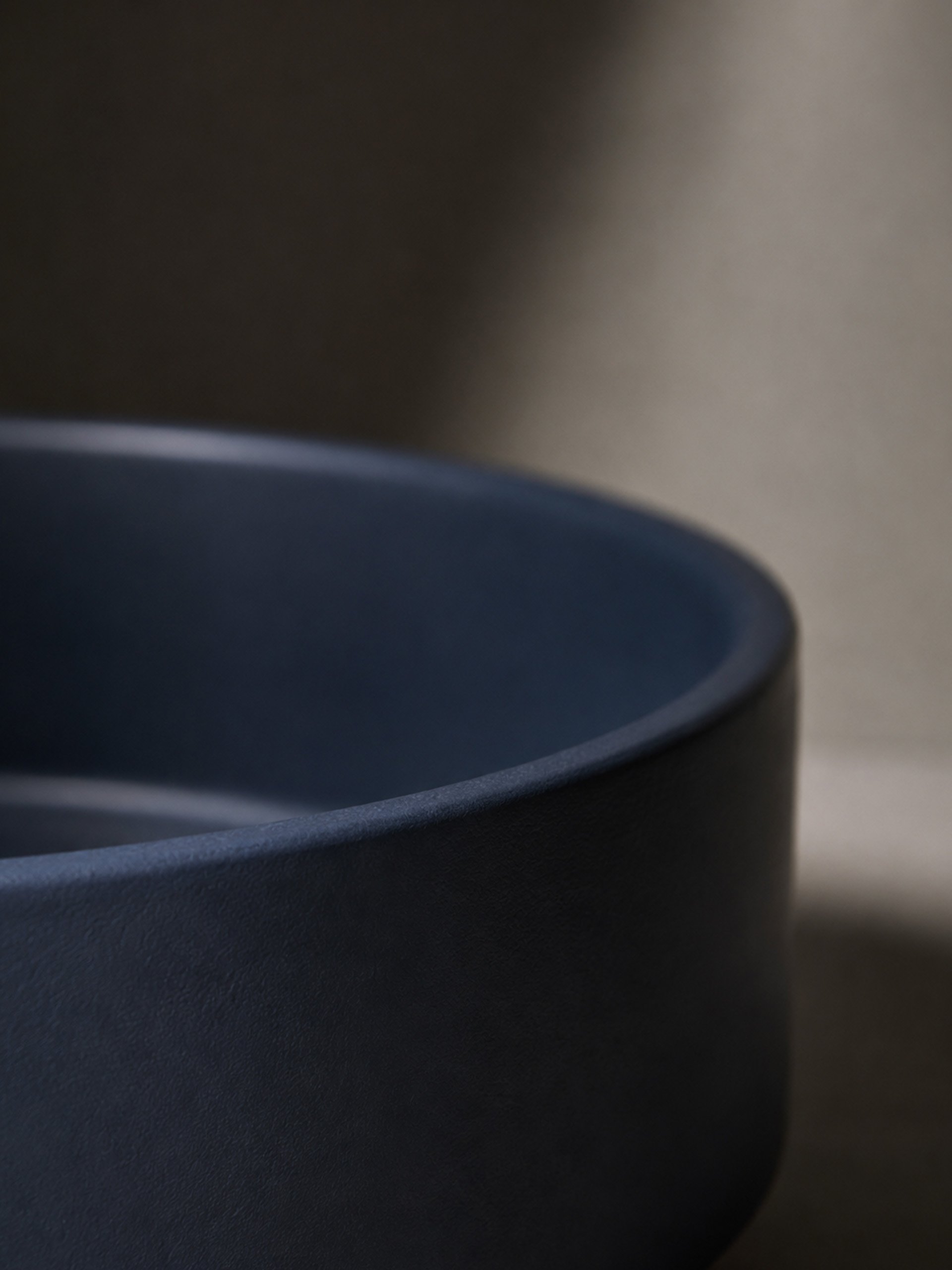 Close-up detail of a deep blue concrete sink highlighting the softened edge and textured matte surface.