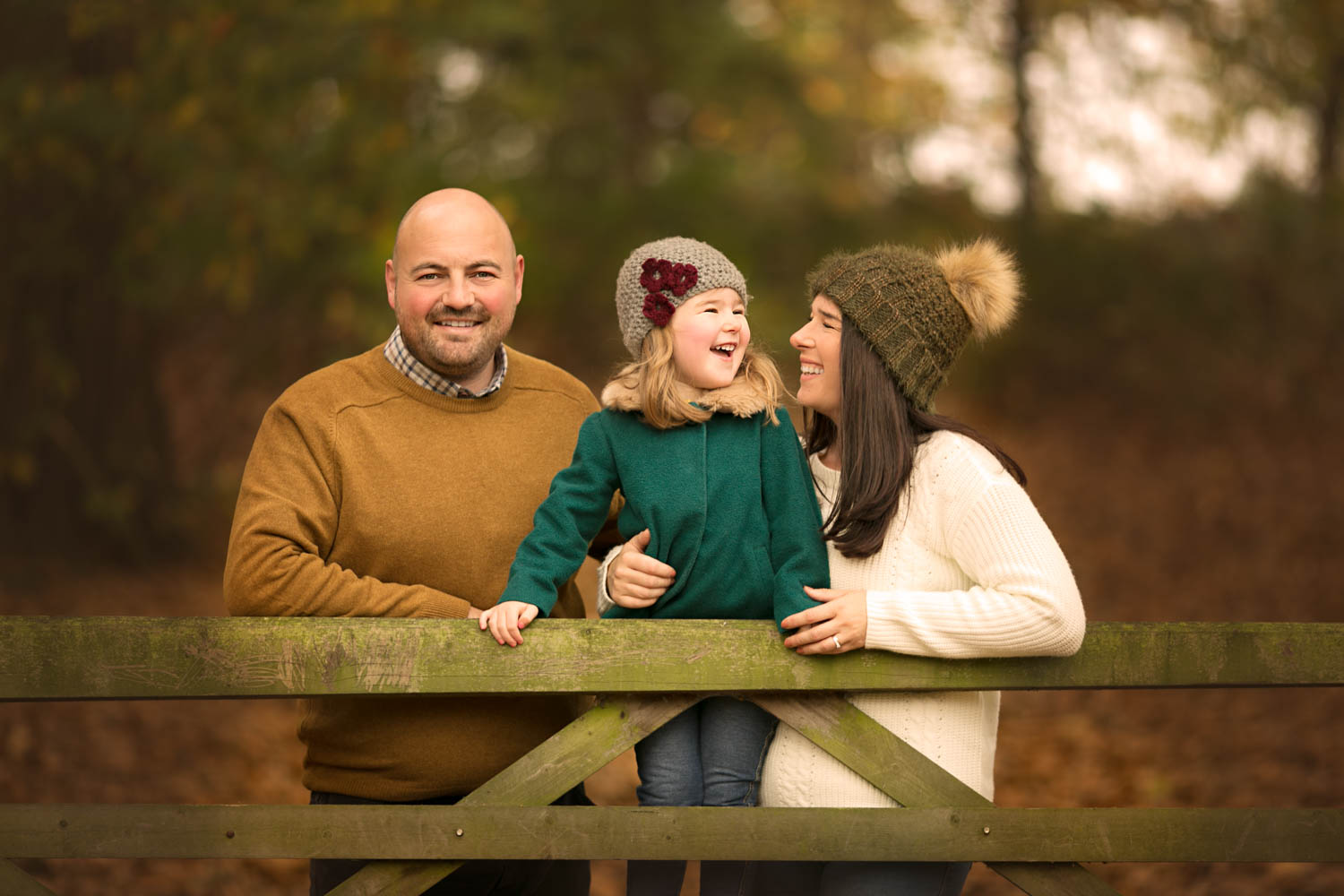  Family posing against gate during an Autumn family photoshoot at Ampthill Park in Bedford. 