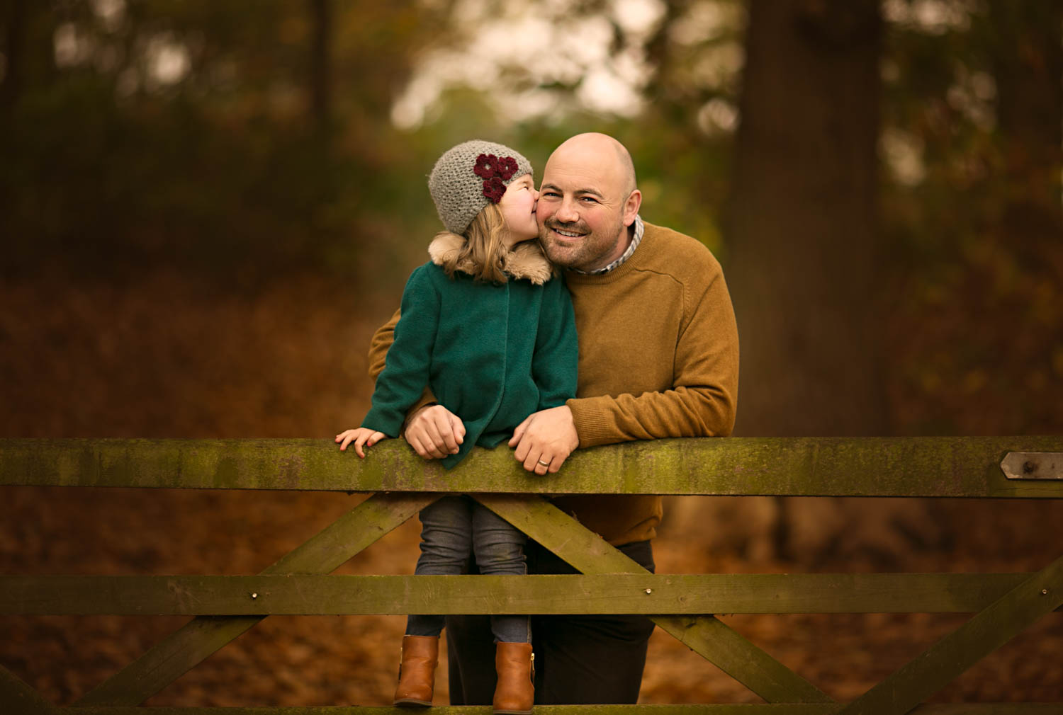 Father and dughter posing against a gate during an Autumn family photoshoot at Ampthill Park in Bedford.