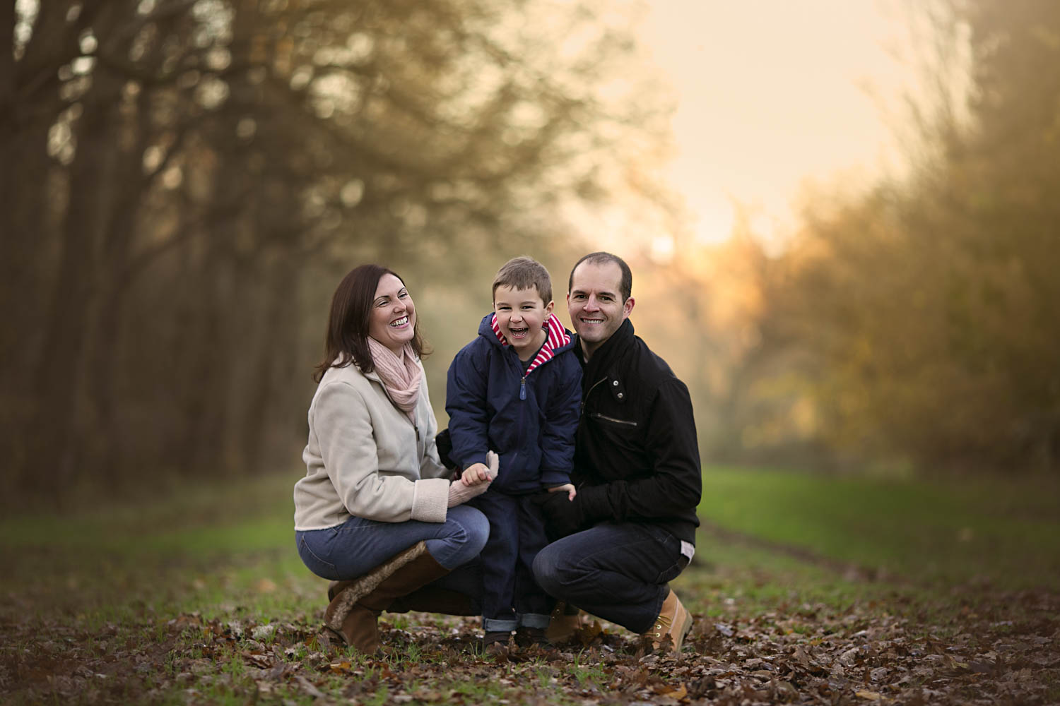  Mother, father and son posing for a family portrait in the golden hour on a autumn photoshoot in Milton Keynes. 