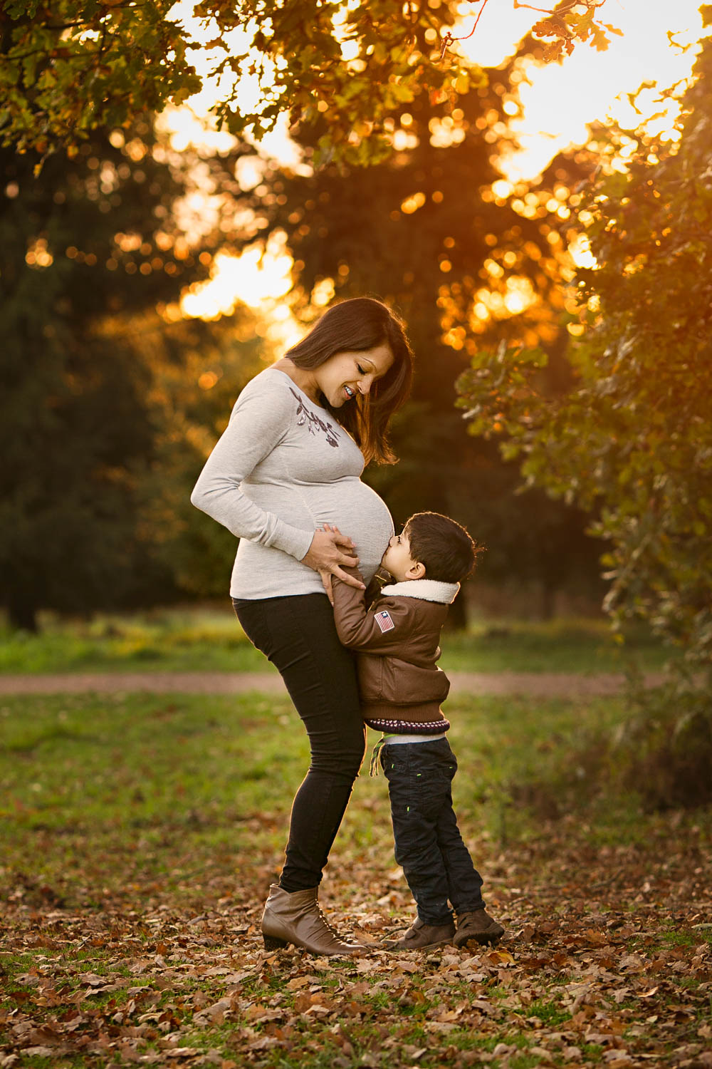  Pregnant mother and son kissing bump during a Family Autumn photoshoot at Rushmere park in Bedfordshire. 