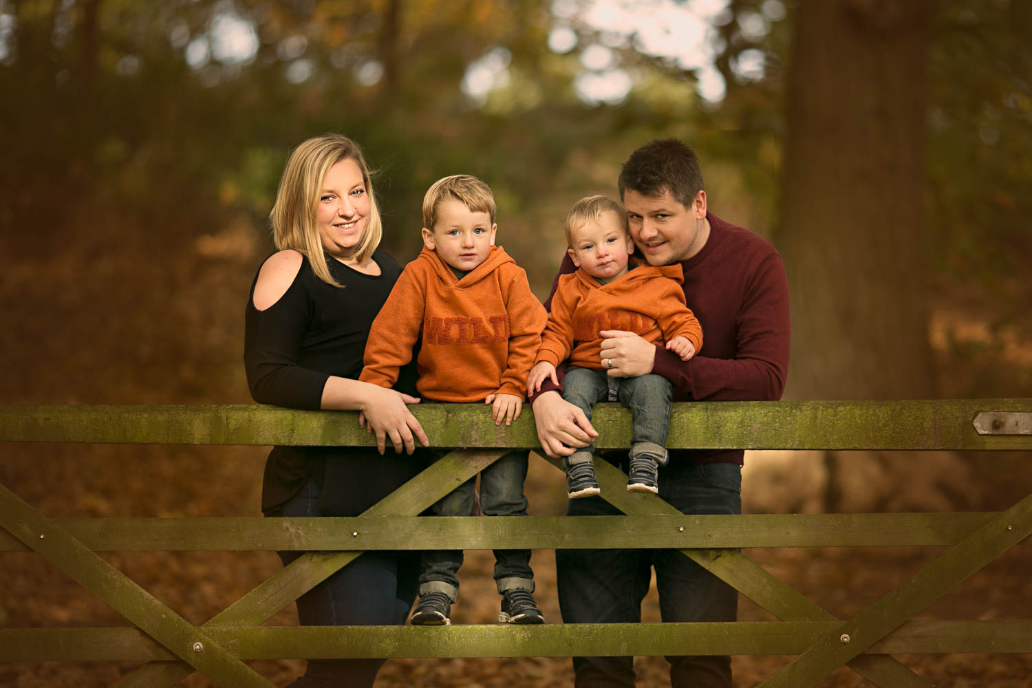  Family posing againgst a gate during family portrait session at Ampthill Park in Bedford. 