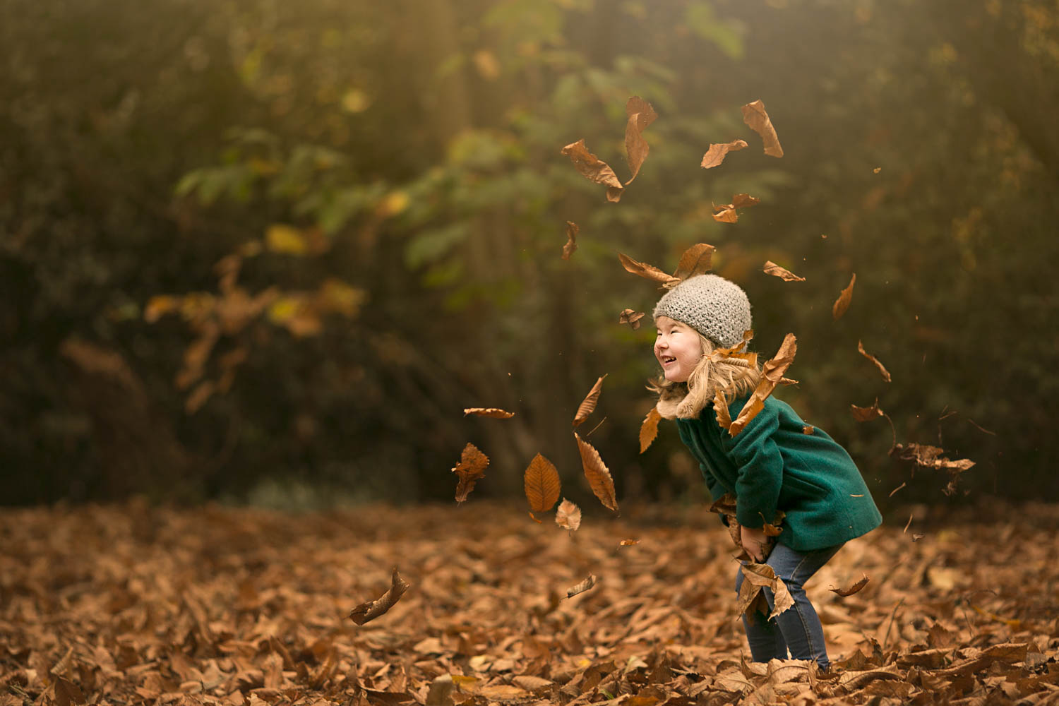  Young girl throwing leaves in Autumn family photoshoot at Amphtill Park in Bedford. 