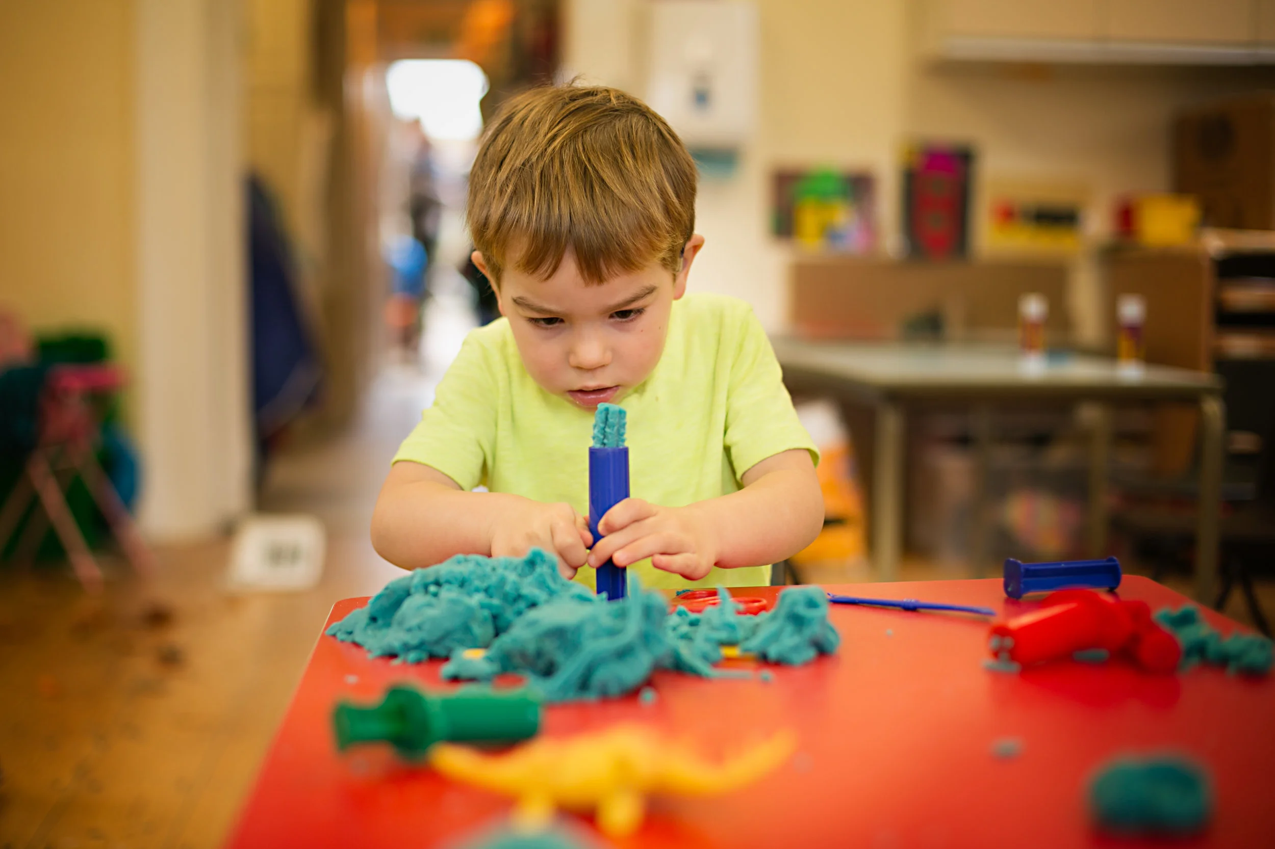 A portrait of a child at Turvey preschool playing with playdough during a Preschool photoshoot - Bedford.