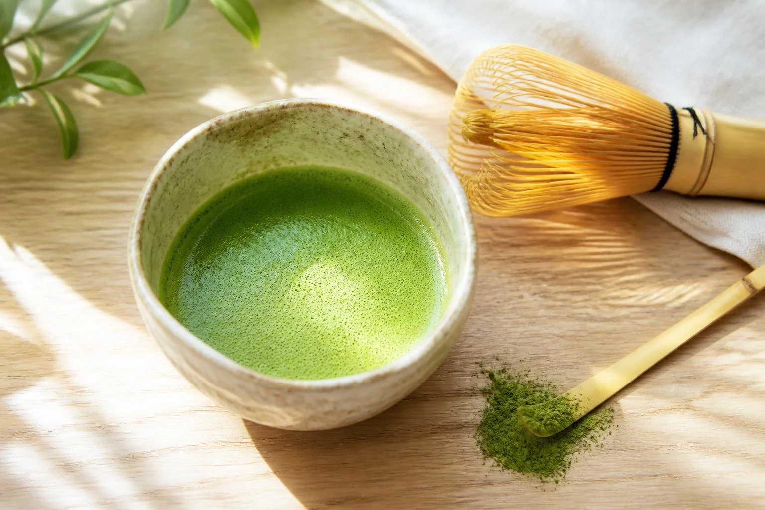 A bowl of whisked Matcha Samidori with a bamboo whisk and scoop