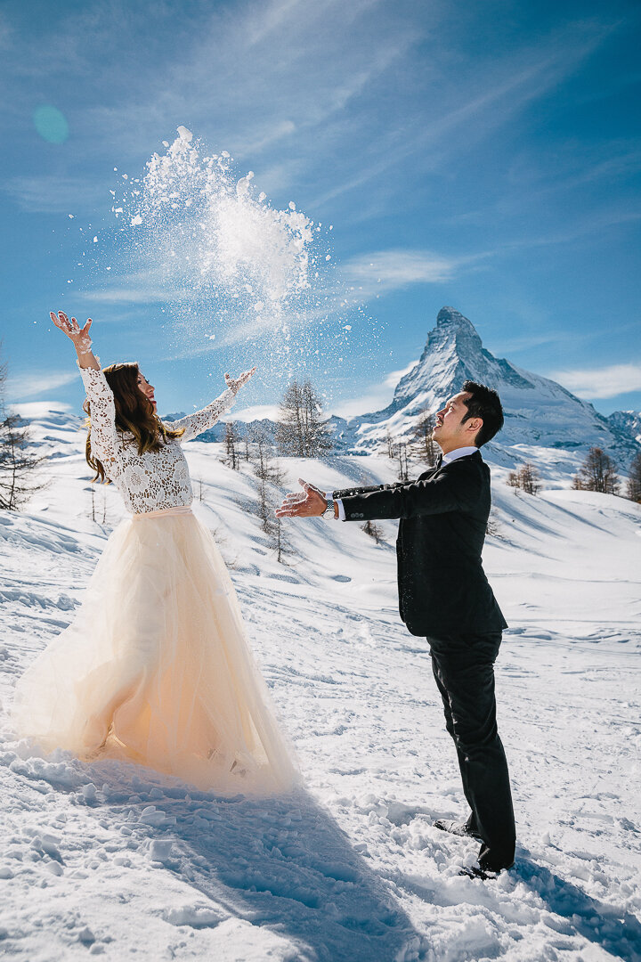 A couple enjoy a moment of pure joy in the snow in Zermatt while taking pictures for their engagment shoot