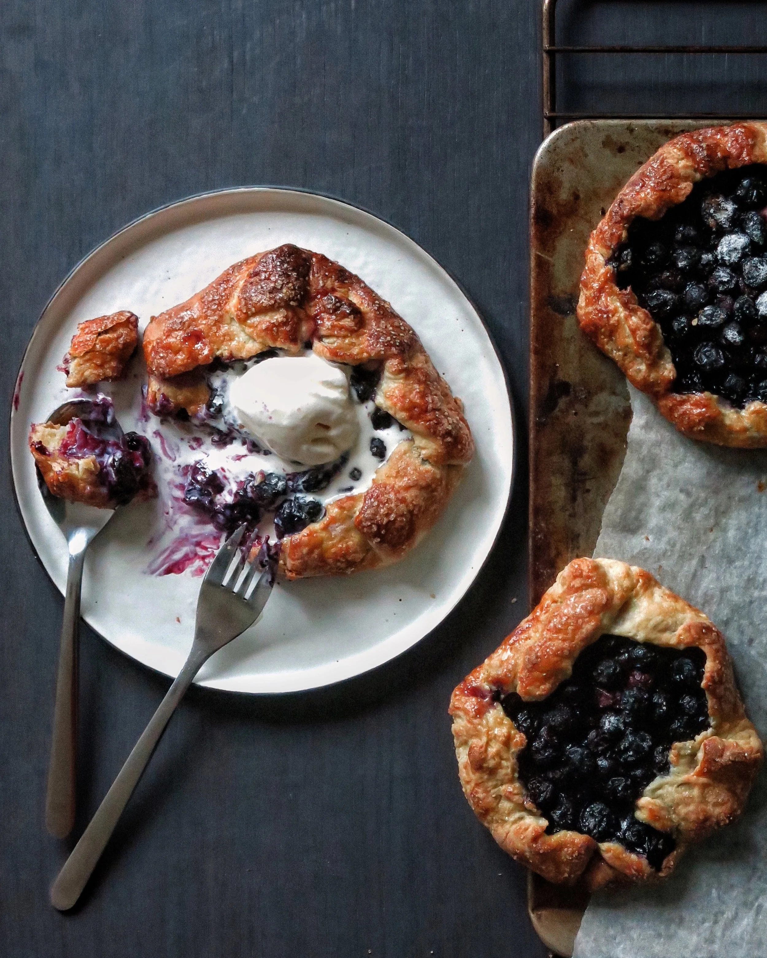 Ingredients 113g Unsalted Butter (cold) 155g Plain Flour 1/2tbsp Caster Sugar 1/2tsp Salt 1/2 Cup Buttermilk 260g Blueberries 1 Apple 30g Caster Sugar 1tbsp Cornstarch 1tsp Vanilla Extract Zest 1 Lemon 1 Egg Raw sugar to finish Method 1. Begin by making the dough. Mix together the flour, sugar and salt. Add the cold butter in cubes and toss to coat. Tip all the mix onto a floured surface and, using a rolling pin, roll out creating strips of butter through the flour. Gather together and continue to roll out a couple of times until the butter is evenly distributed through the flour. Place the mixture back in the bowl. 2. Create a well in the centre of the flour and butter mixture and add the buttermilk. Gently bring together into a dough. Divide the mix into three or four and press into a disk. Wrap in cling film and place in the fridge for at least an hour. 3. Combine the blueberries with the sugar, cornstarch, vanilla and lemon zest. Cut the apple in half and thinly slice on a mandolin. 4. To assemble, roll the pastry discs out to make a circle of around 8” and, in the centre, place a few slices of apple (ensure you leave a 2” space around the edge. Top the apple with the blueberry mix and roughly fold the pastry edges up to partly cover the filling. This doesn't have to be neat, in fact, it should look a little rustic. Brush the pastry with some beaten egg and sprinkle with raw sugar. Place in a preheated oven at 200 degrees and bake for 30 minutes or until golden and brown and bubbling. Serve warm with ice cream.