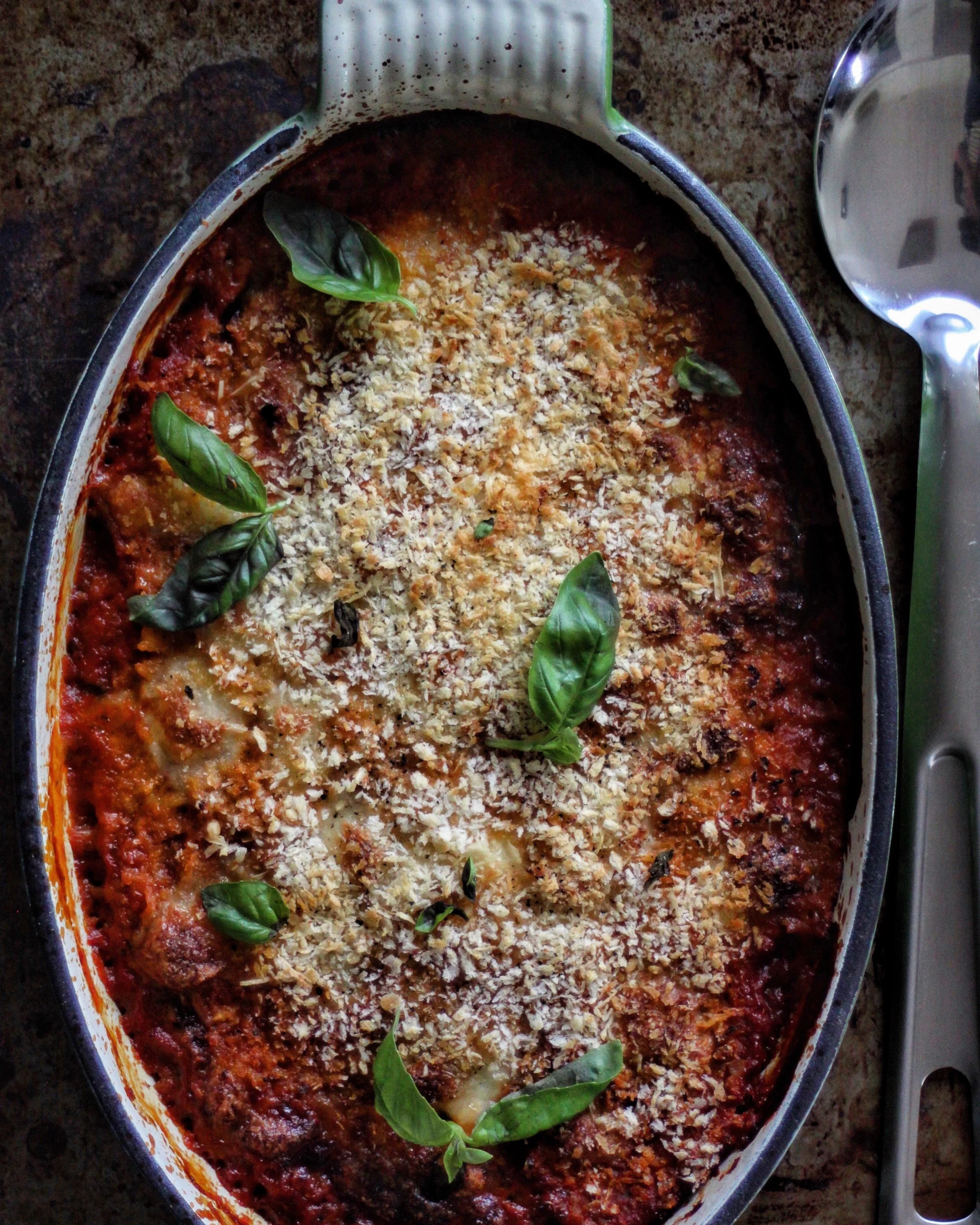 Ingredients 3 Large Aubergines (Eggplant) 1 Onion 1 Clove Regular Garlic 2 Tins Plum Tomatoes 1 Pinch Sugar 1 Handful Fresh Basil 100g Grated Parmesan Cheese 125g Mozzarella Handful of Dried Breadcrumbs (optional) Method Begin by preparing the aubergines. Remove the stalk and slice lengthways into 1cm slices. Brush with a little olive oil. Make the sauce by finely slicing an onion and softening it in a pan with a little olive oil and a crushed clove of garlic. Once the onion and garlic begin to give off their aroma, add the tinned tomatoes, break them up gently, add a pinch of sugar (to balance the tartness of the tomatoes) and simmer the sauce for 15 minutes. Whilst the sauce is cooking, place the aubergine slices in a hot pan and cook them until soft and slightly charred. You may have to do these in batches. Once all of the aubergine is cooked, set aside. Finish the sauce off with some torn fresh basil and a generous seasoning of salt and pepper. Use a hand blender to make the sauce smooth and creamy. Take an ovenproof dish and begin to assemble. Start with a layer of the tomato sauce, a sprinkling of grated parmesan and then a single layer of aubergine (like a lasagna). Repeat the layers as before until all ingredients are used up - finishing off with a layer of sauce and a sprinkling of parmesan. At this stage you can tear the mozzarella and place on top of the parmigiana. Alternatively, you can just finish with some dried breadcrumbs (or just sprinkle them over the mozzarella). Bake in a preheated oven at 190 degrees for around 30 - 40 minutes. Best served warm.