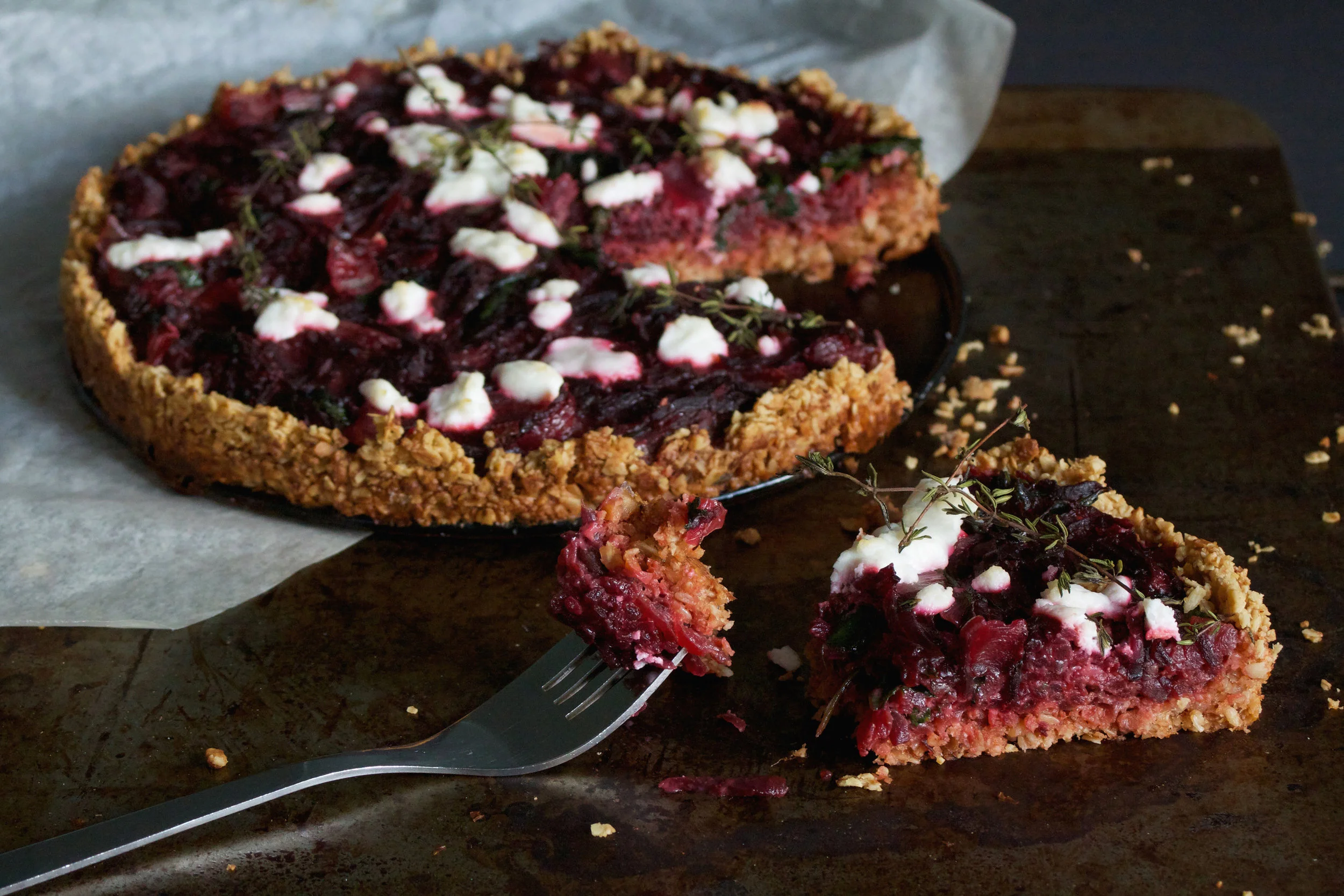 Ingredients For the crust: 1 Cup Rolled Oats 1/2 Cup Raw Cashew Nuts 3 tbsp Cold Butter 1 Sprig Chopped Thyme 1 Pinch Salt 2tbsp Cold Water For the filling: 250g Cooked Beetroot 1 Small Onion Chopped 1 Large Clove Garlic 2/3 Sprigs Thyme 1 Large Handful Fresh Spinach 2 Large Eggs 125mls Milk 80g Goats Cheese Method Begin by making the crust. Toast the cashews for a minute in a dry pan until toasted. Allow to cool. Place the oats, cooled nuts, butter, thyme, salt and water into a food processor and pulse into a soft sticky dough. Wrap in cling film and allow to chill in the fridge for 30 minutes. Whilst the dough chills, make the filling by grating the cooked beetroot (I use the grater attachment on the food processor to save mess). Place the chopped onion into a frying pan with a drizzle of olive oil and the crushed garlic. Pick off the thyme leaves and add them to the pan. allow to cook for a minute or two and add the spinach. Wilt the spinach down and then add the grated beetroot. Cook all the ingredients for a further 2 minutes and place in a bowl to cool. Once chilled, press the dough, using your fingers into a 9 inch tart/ cake tin. It may look like it wont fit but keep pressing, it fits well and ensures a thin, crisp crust. Place the crust in a preheated oven at 190 degrees for 12-15 minute until golden. Whisk together the eggs and the milk, adding a good pinch of seasoning and then the cooled beetroot mixture. Once the crust is golden and cooled slightly, pour the filling inside and top with pieces of goats cheese and a couple of extra sprigs of thyme. Turn the oven down to 180 and cook for 25-30 minutes until set. Serve with salad for the perfect winter lunch.