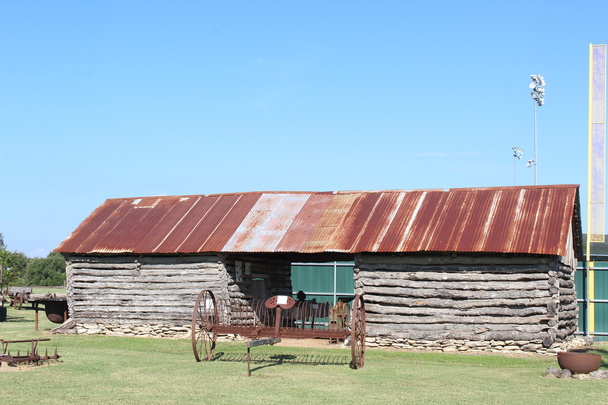 The authentic circa 1904 double-log corn crib with dog trot was constructed with hand-hewn logs joined with simple saddle notching. A central passageway allowed for easy loading/unloading of wagons to or from a crib on either side. The Log Crib was donated by Hilda Fajkus and Sylvia Ratcliffe of Cistern. It was moved to the site by Káňa Brothers Moving Company and restored by brothers Ed, Ernest, David, and Robert Vašek of Plum, and Robert Stall of Smithville with replacement logs donated by Vickie Matocha and Jeb Pape.