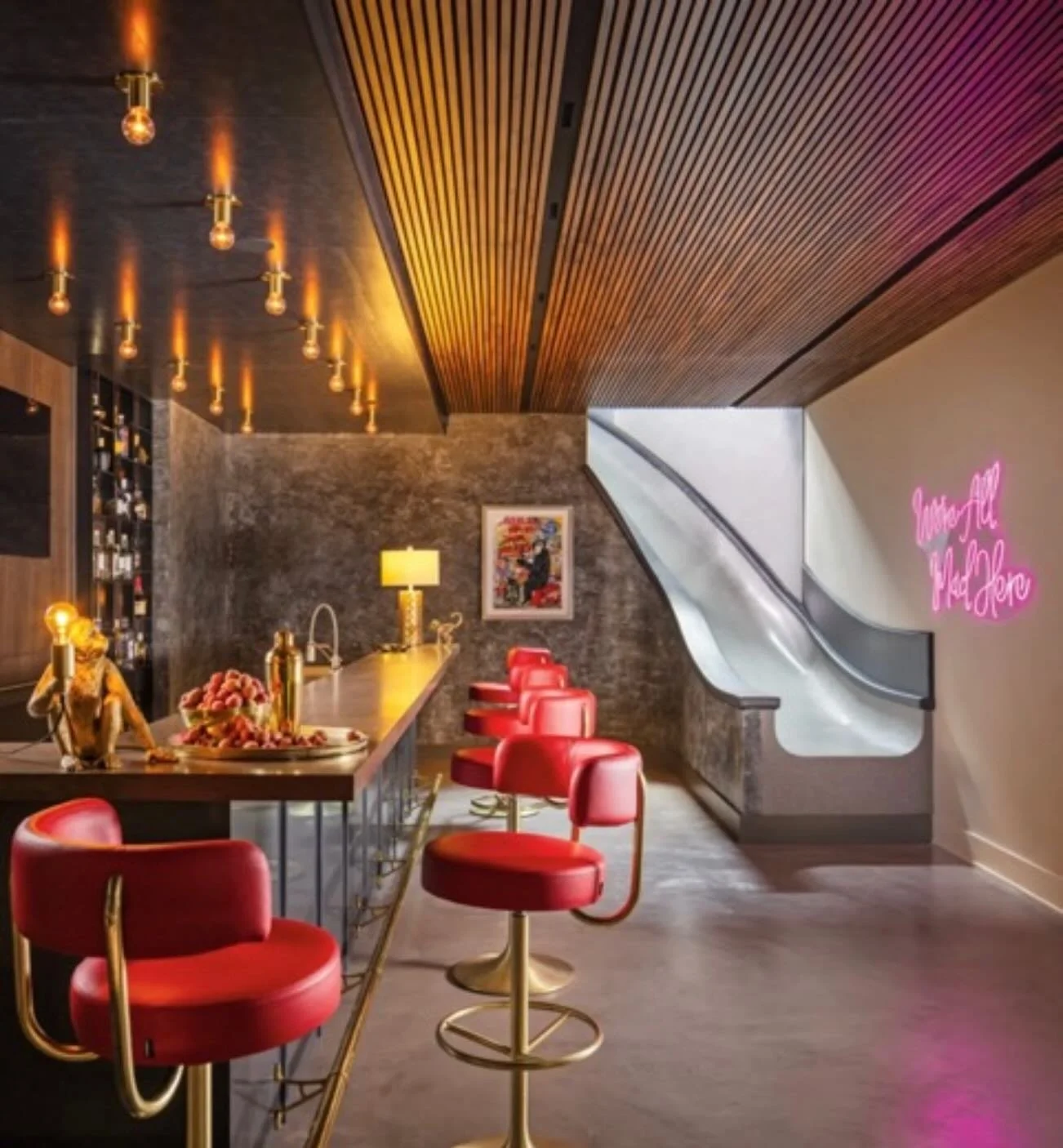 How fun must the people be who live in a home that has a speakeasy on the lower level that you access by a slide! (There is a staircase alternative) The owners are also telling you in the neon sign, &ldquo;we&rsquo;re all mad here&rdquo;. When your h