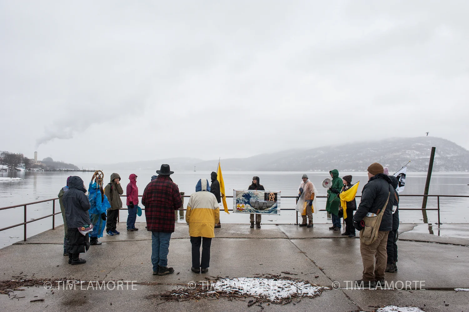 Maria Maybee leads a water ceremony at Peekskill Landing Park, north of Indian Point’s two domed reactors to the left.