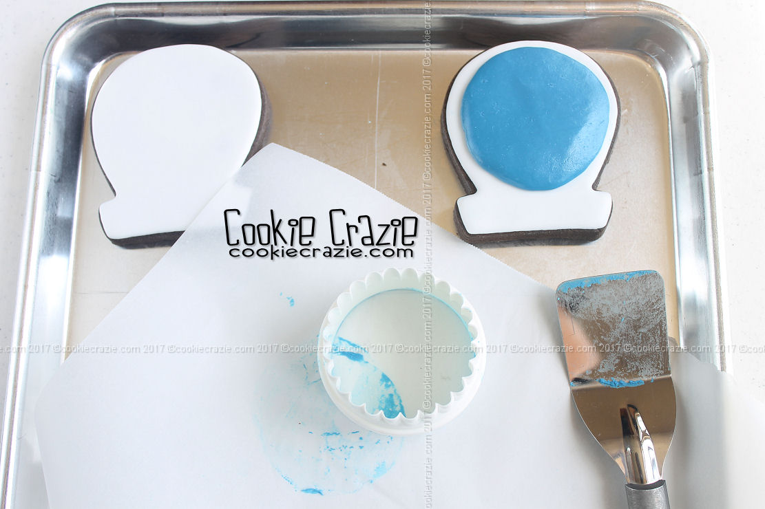  Use a thin spatula to carefully remove the "globe" from the parchment paper and place it on the large circular area of the cookie. (see photo below) 