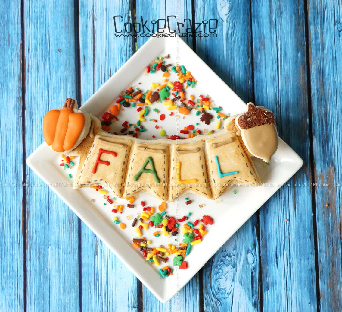 YouTube How To Video found HERE for Fall Bunting Decorated Sugar Cookie Bunting (four spaces) Cutter with mini pumpkin and acorn cookies added to the sides