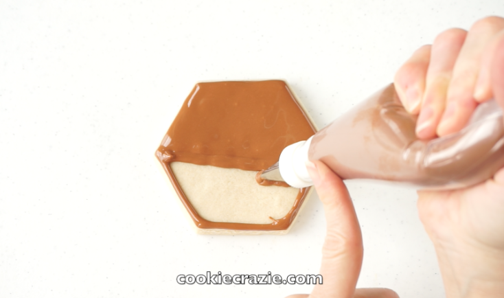  Outline and flood the hexagon cookies with brown glaze.&nbsp; 