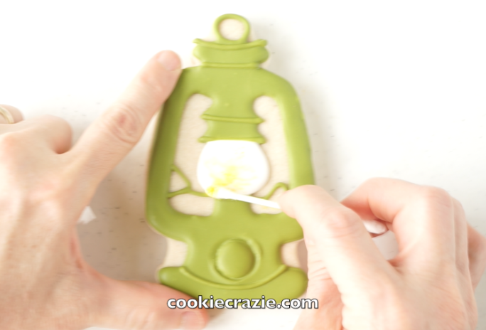  Allow the cookie to dry overnight.&nbsp; Using a cotton swab, spread dry yellow luster dust within the "bulb" of the lantern to give it a lighted effect. (Dust found  HERE ) 