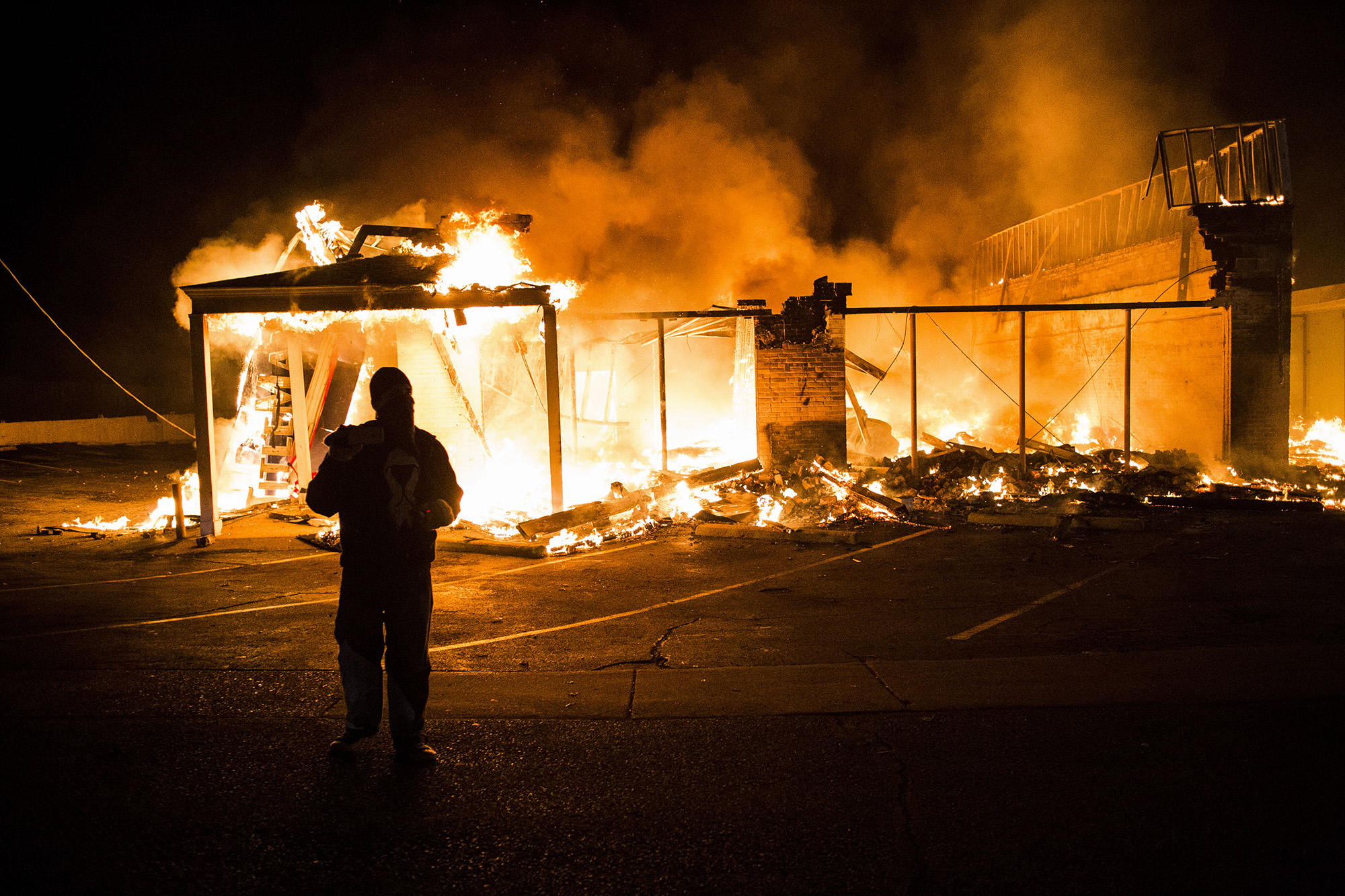  A protester films the scene after protesters set fire to a commercial building on Nov. 24, 2014 in Ferguson, MO.&nbsp; 