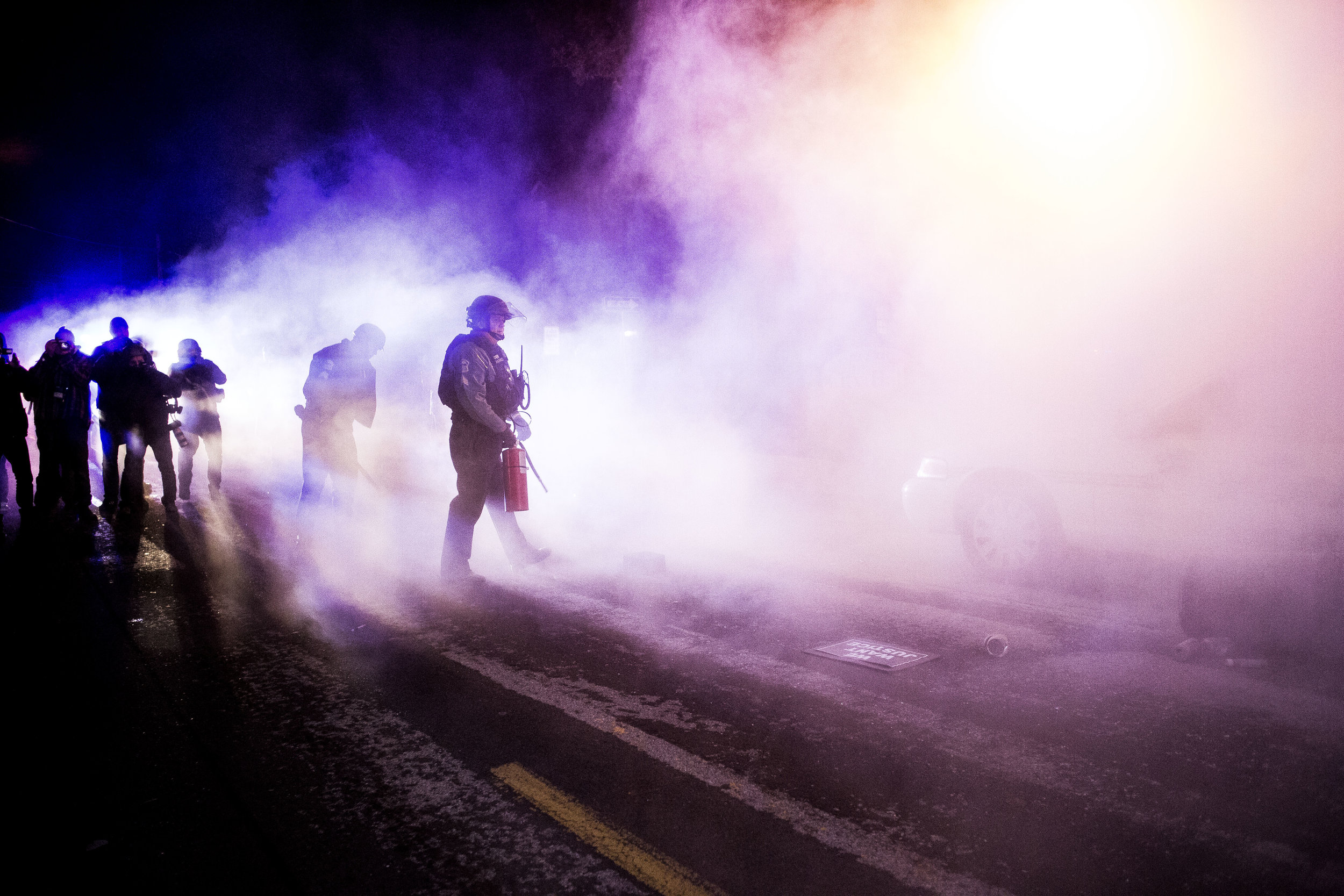  A police official puts out a fire set to a police vehicle outside the Ferguson City Hall on Nov. 25, 2014, in Ferguson, MO.&nbsp; 