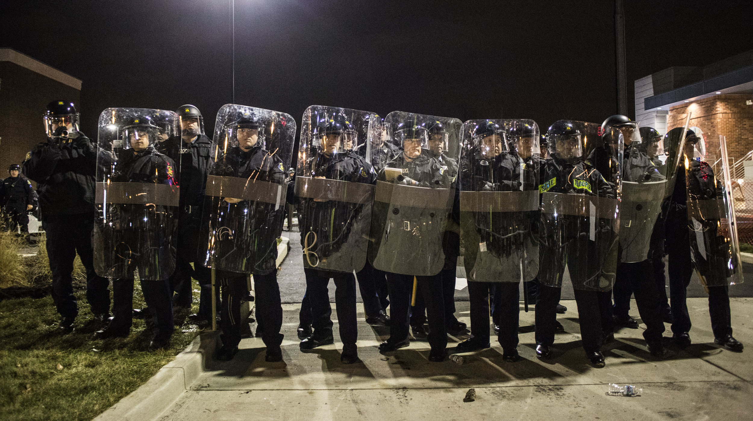  Police guard the Police Department building as protesters throw empty bottles at them on Nov. 24, 2014 in Ferguson, MO.&nbsp; 