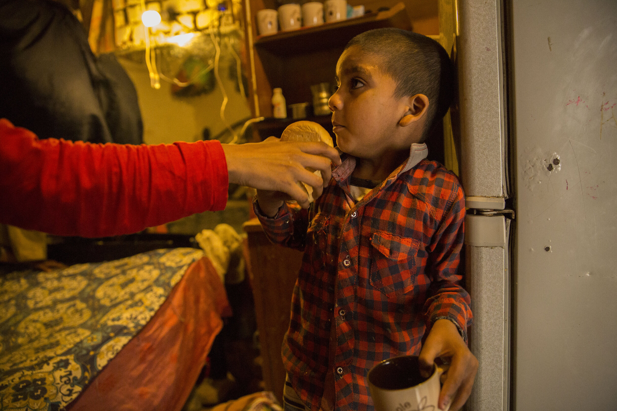 5-year-old Yushya sneaks a few rusks. A 30 cents bag of rusks is rationed in the household because of the tough times the family is going through. 