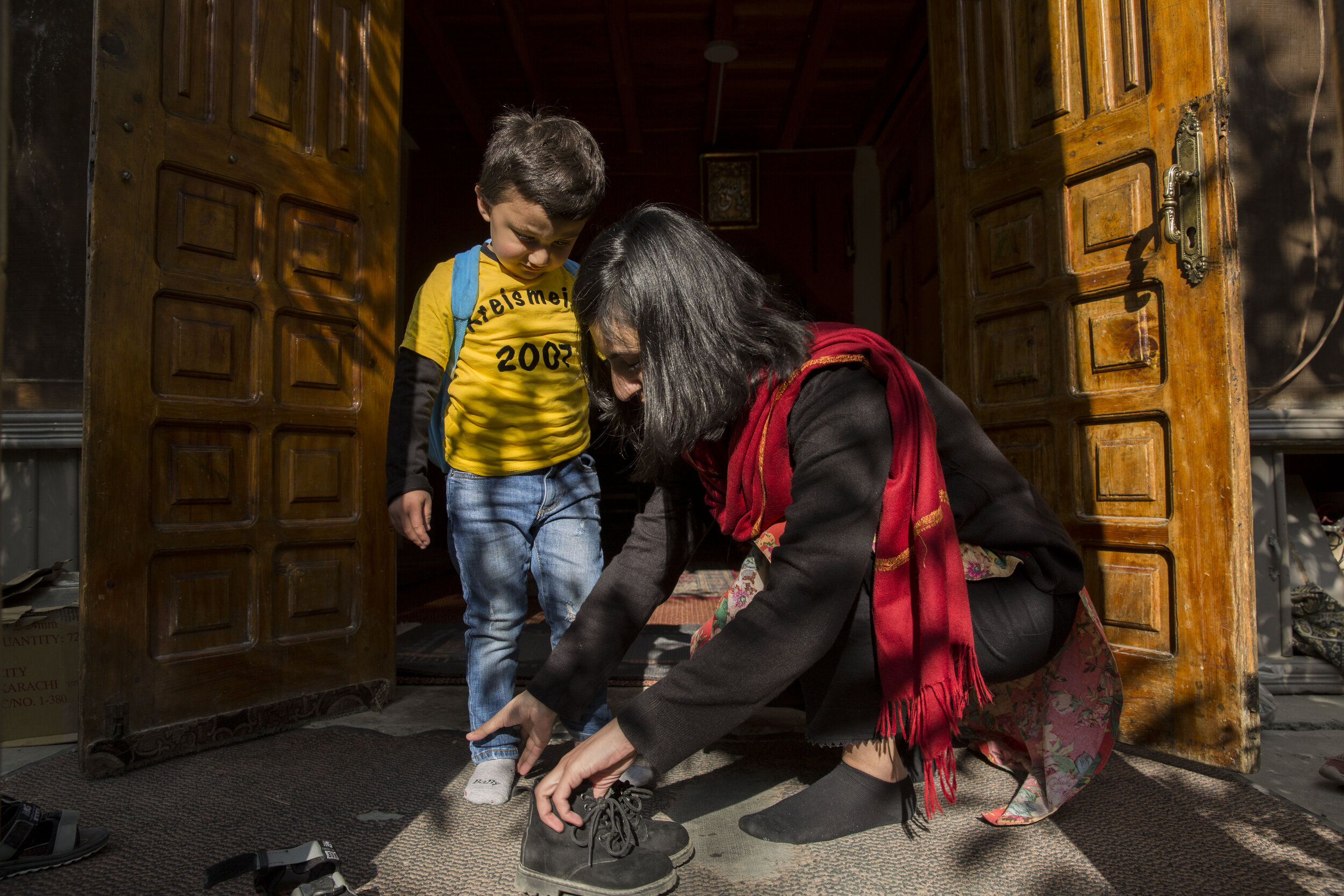  Arifah, a young mother who works for a fintech company, helps her son put on his shoes. 