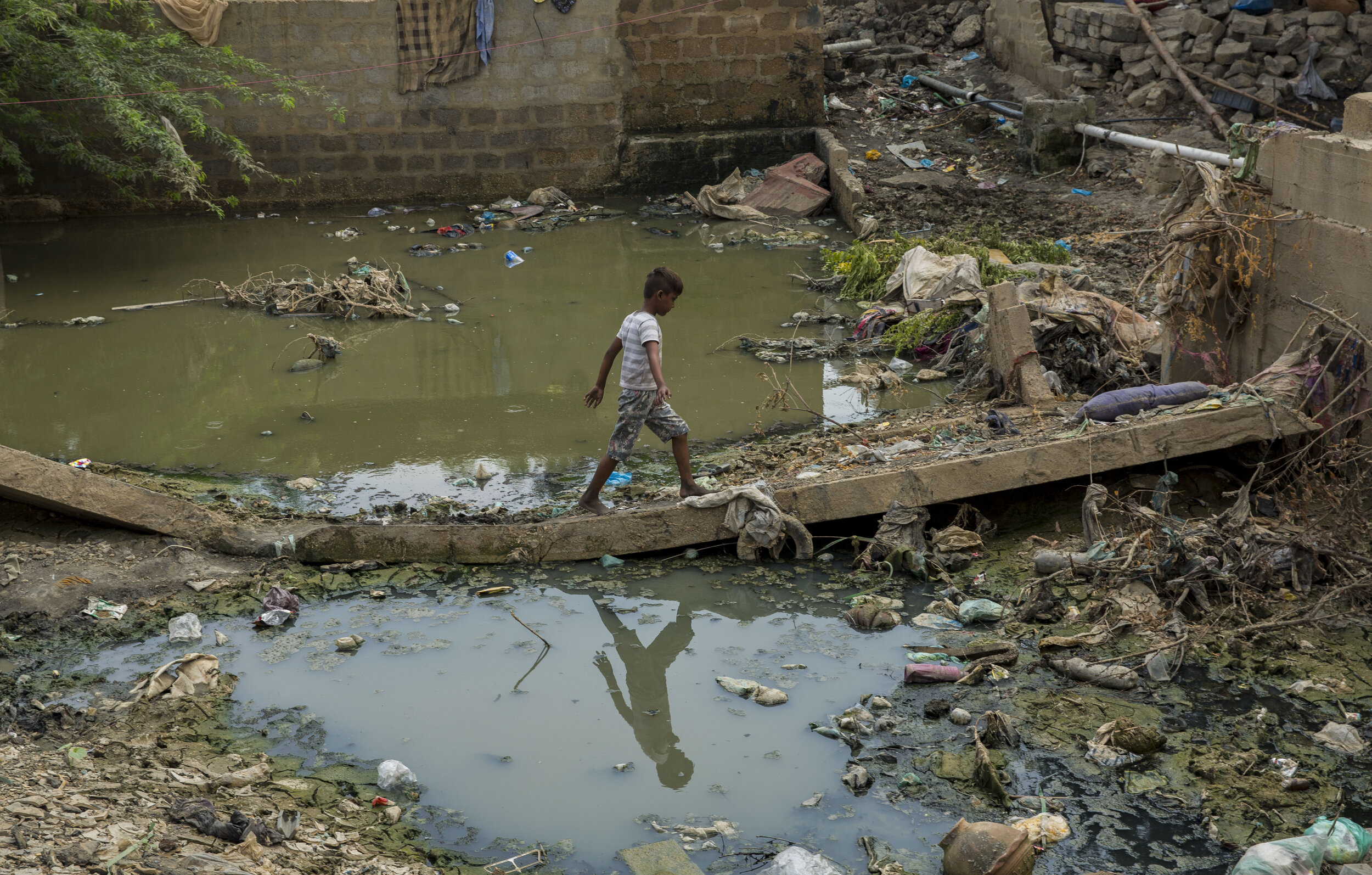  A young boy passes by flood water to go home in one of the slum areas affected by the monsoon floods. 