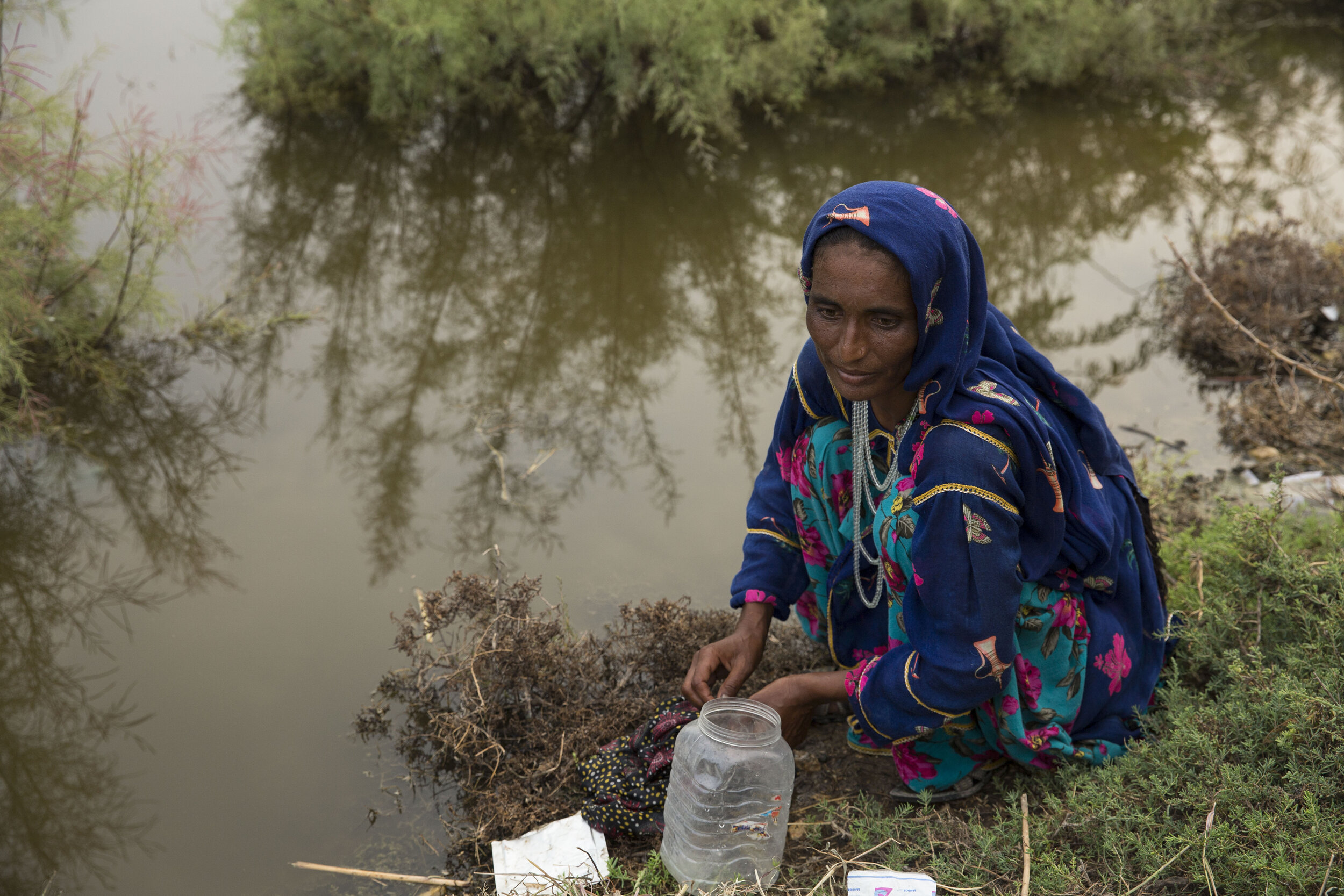  Lateefa washes her clothes with rain-water that is gathered along the expressway as hundreds are camping out due to their homes being devastated. 