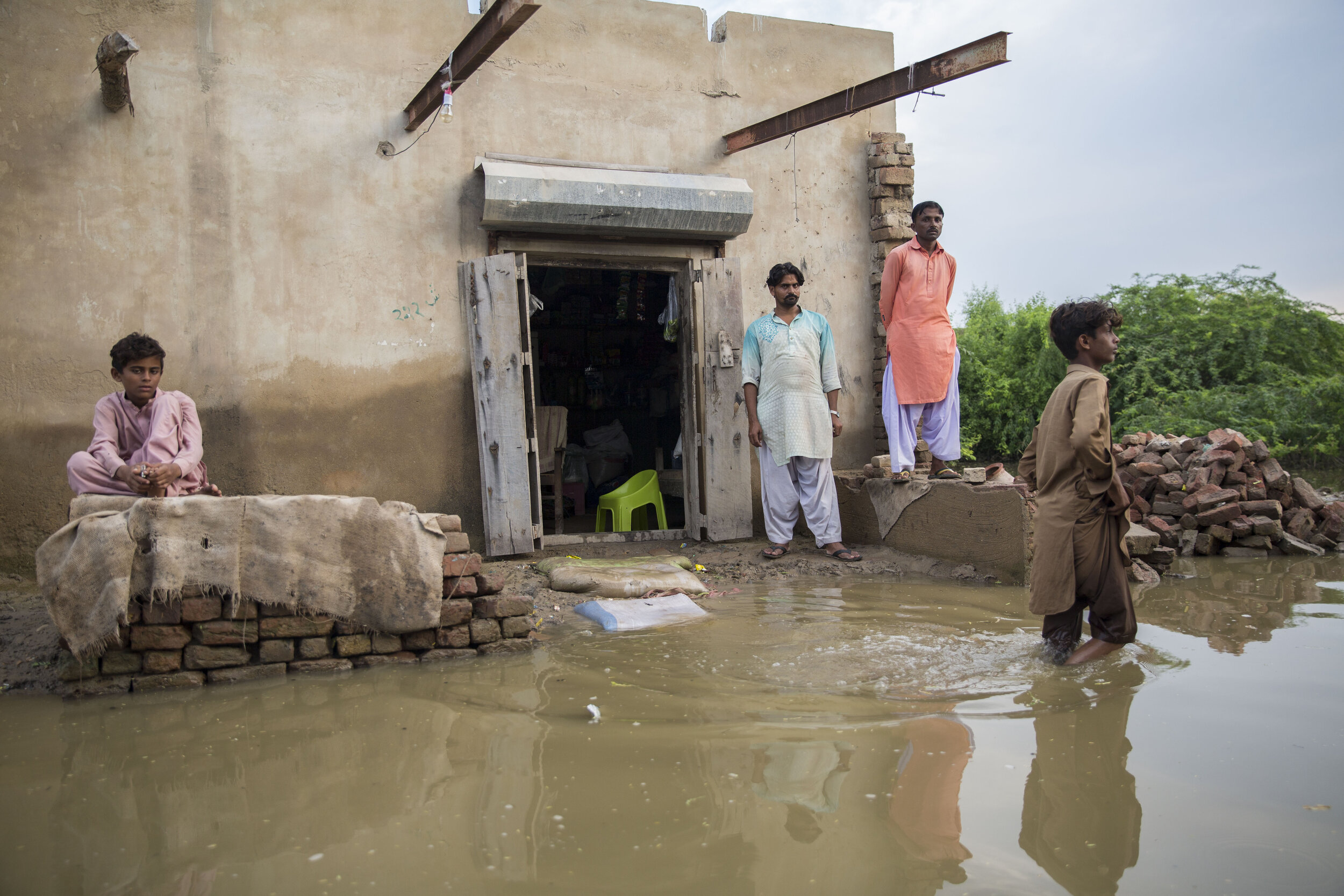  Men stand outside a flooded house in scenes from one of the worst-hit areas due to the recent monsoon floods. 