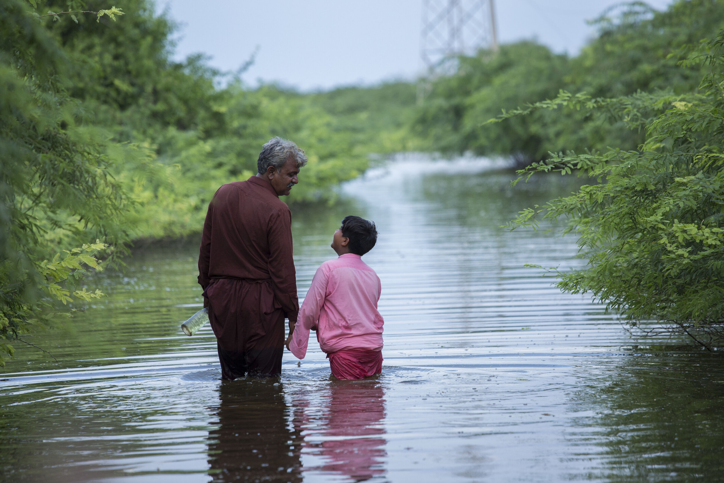  Abdul Jabbar and his son Muhammad Hashim walk across flood water after their home was devastated in one of the worst-hit areas. 