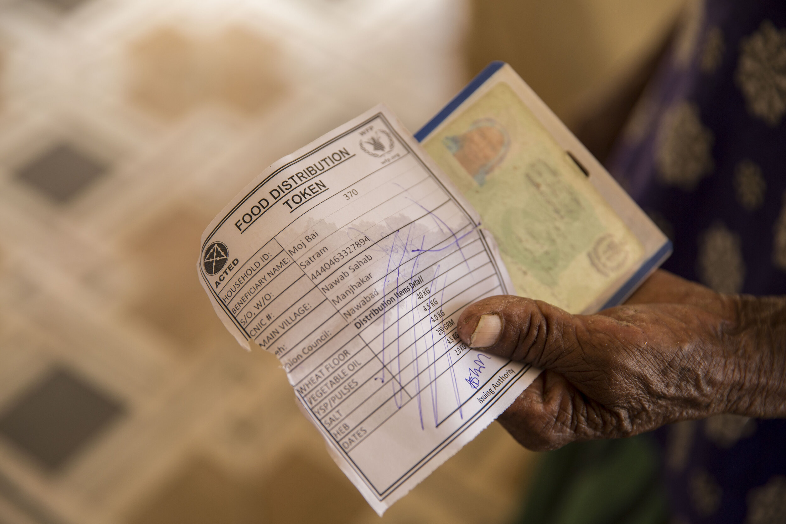  A woman holds a food distribution token to get registered at a general food distribution point for flood affected families.  