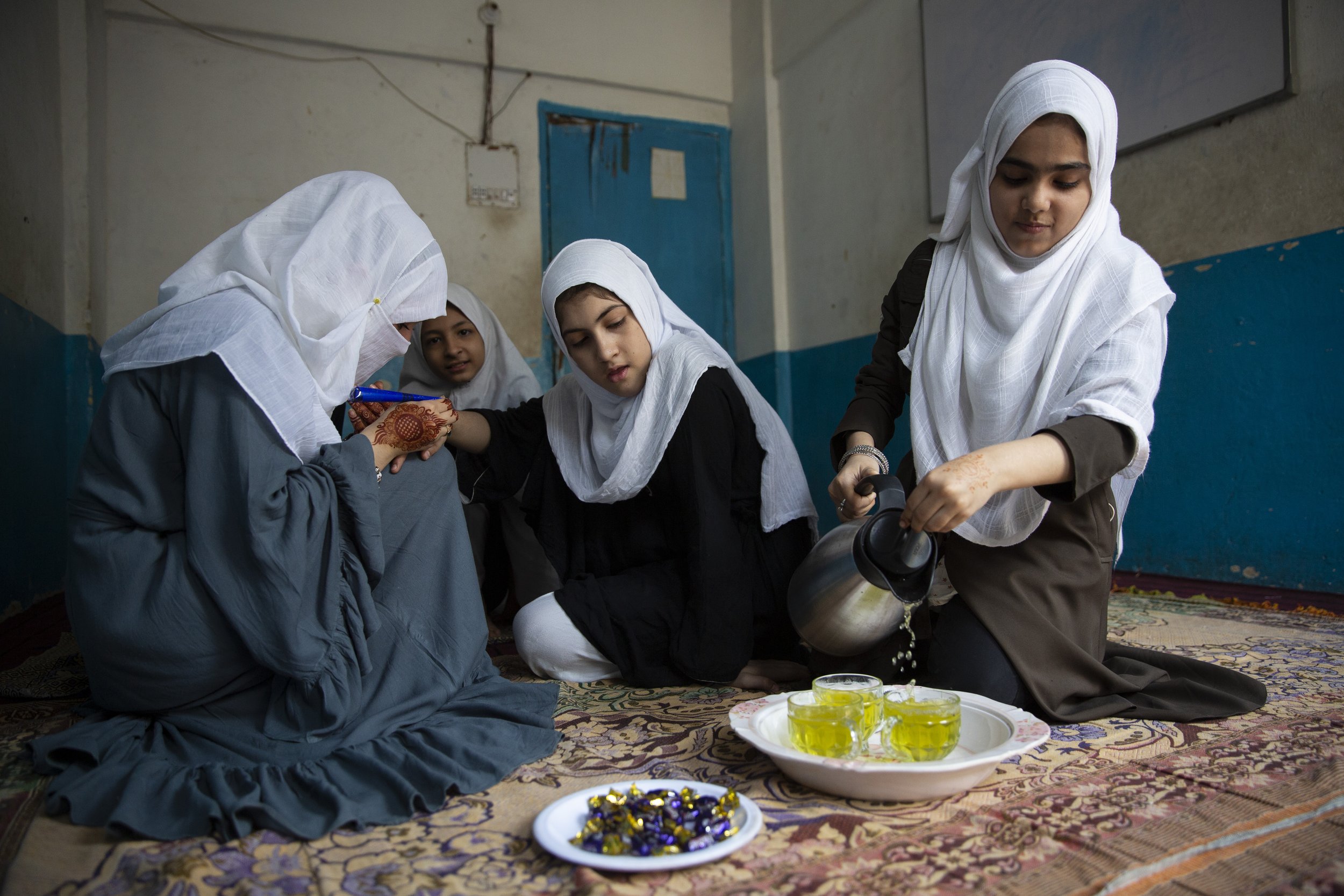  Sameera Wahidi applies henna to another student while they have green tea.  