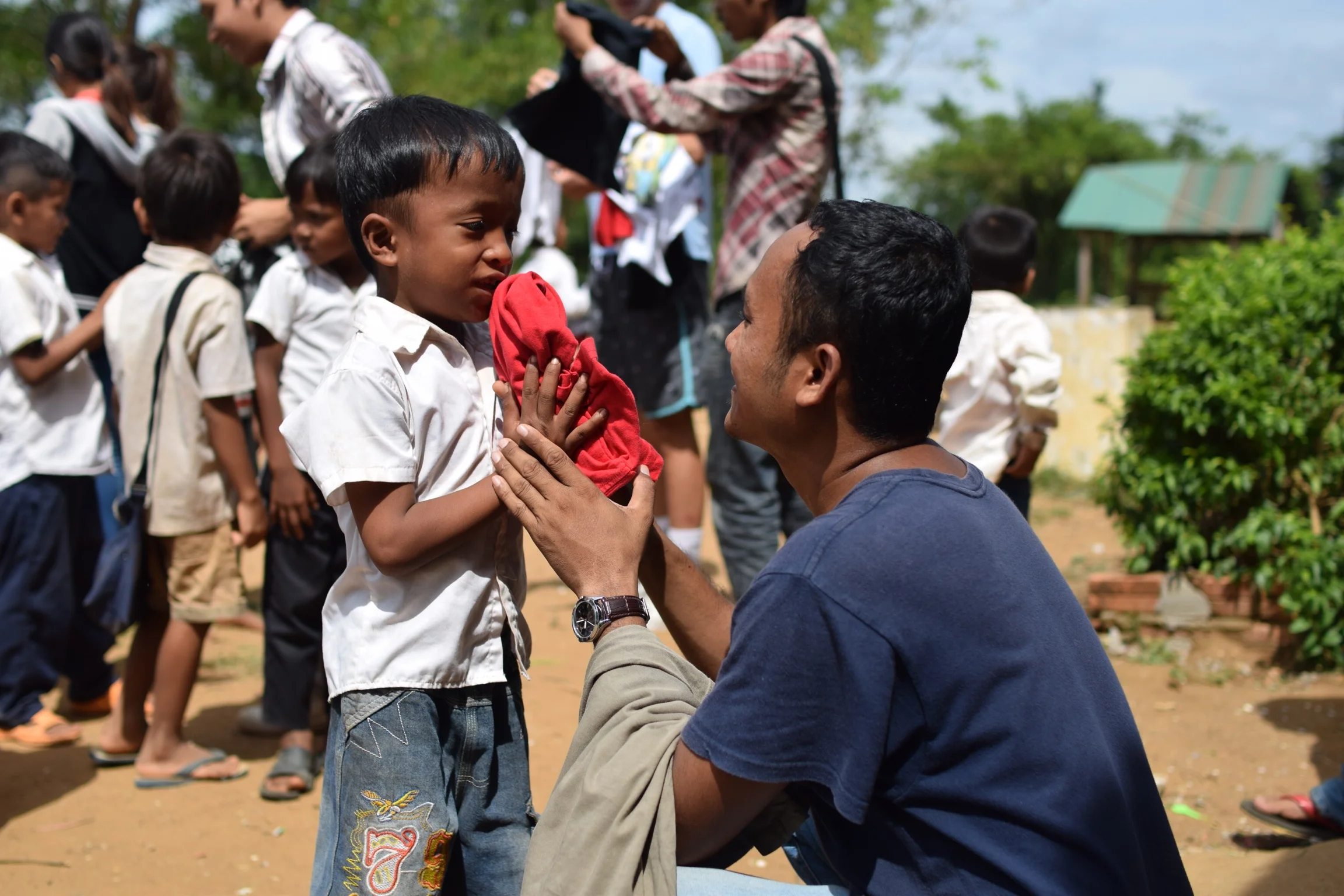 Teacher Phyrom giving clothing to a student at the Kamping Puoy TASSEL School. 
