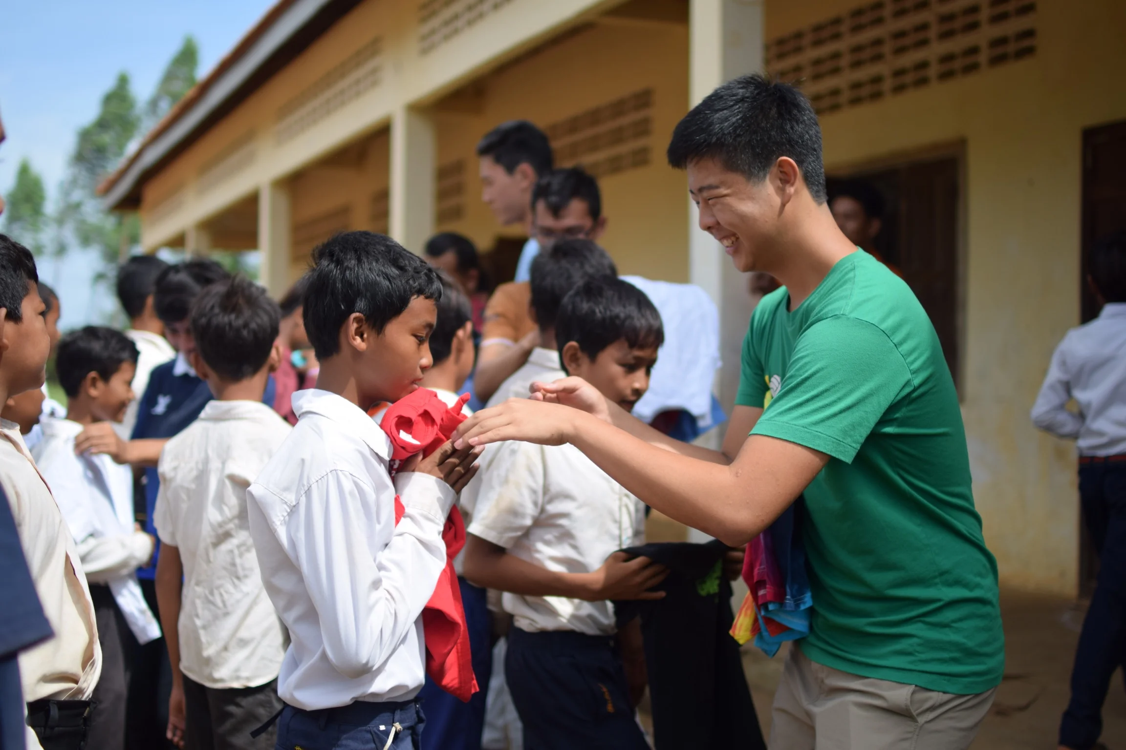 TASSEL volunteer Adam Kim distributing clothing to the students of the Banan TASSEL School, 2016.