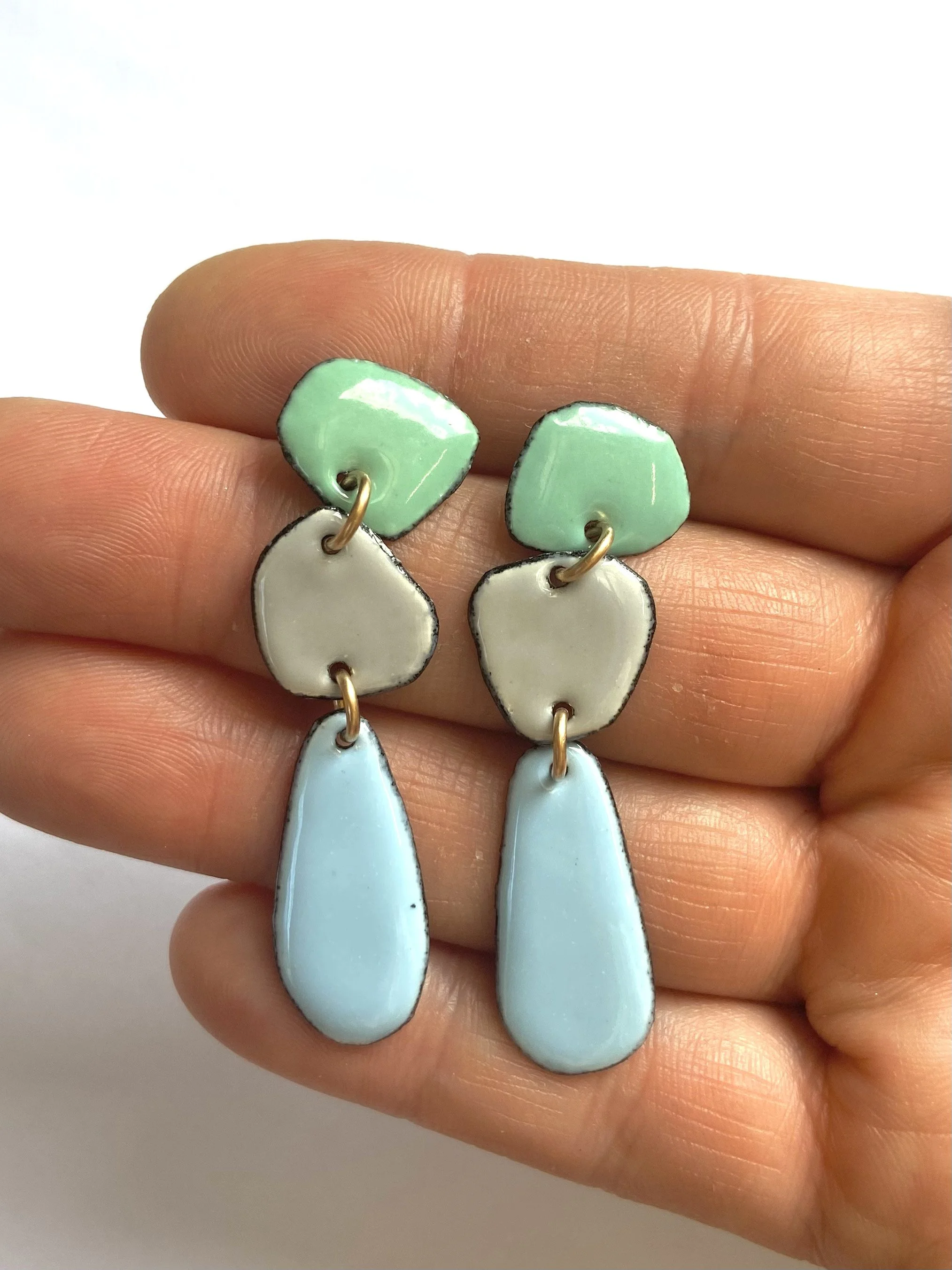 Long skinny pastel cavemen earrings hand.jpg