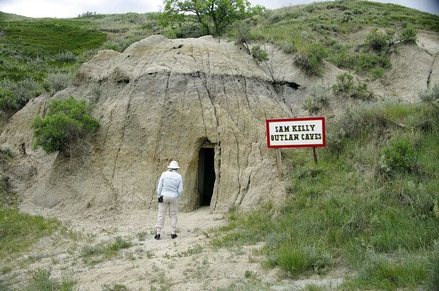 A person standing by a cave used by outlaw Sam Kelly, located in the badlands near Coronach, Saskatchewan.