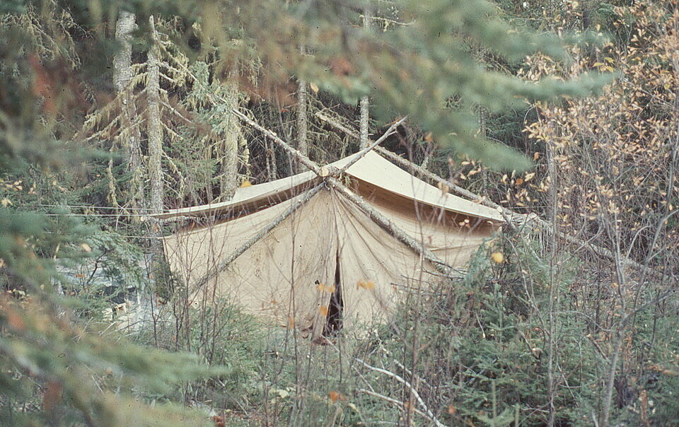 Photo 1: Our white (more or less) cotton tent nestled among the trees the day before the snow storm. This two-person camp was our base for the geological mapping project in the area. Image by Andy Fyon, Hill Lake, northern Ontario, Oct. 1976.