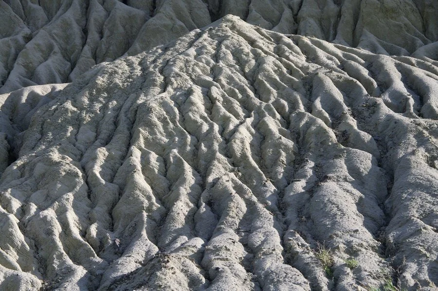Erosion of the badlands continues today and is demonstrated by erosional rills, or mini-gullies, that are created by runoff from prairie thunder storms. Image by Andy Fyon, June 14, 2012.