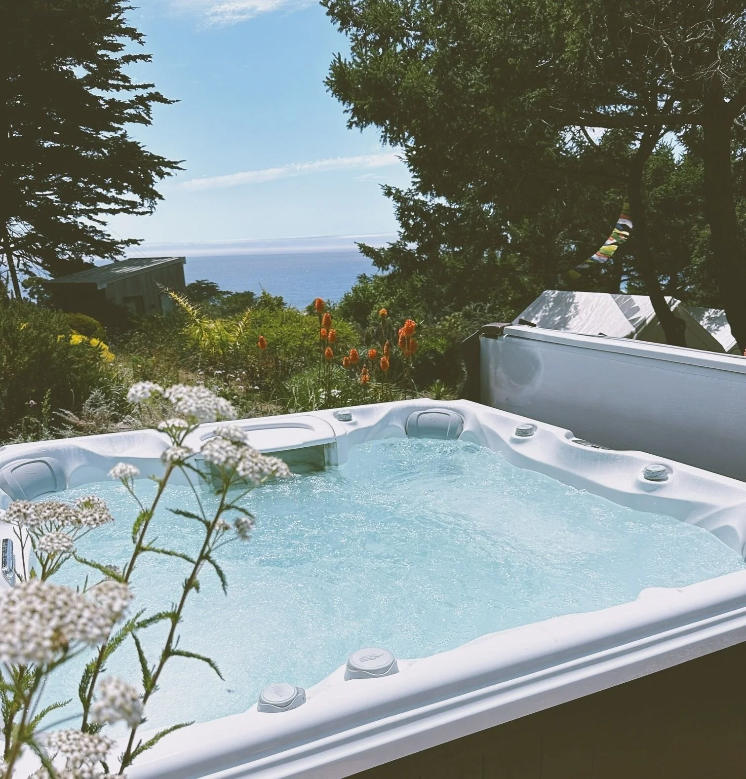 A hot tub  with a view of the ocean and lush greenery. A moment to rejuvenate. 