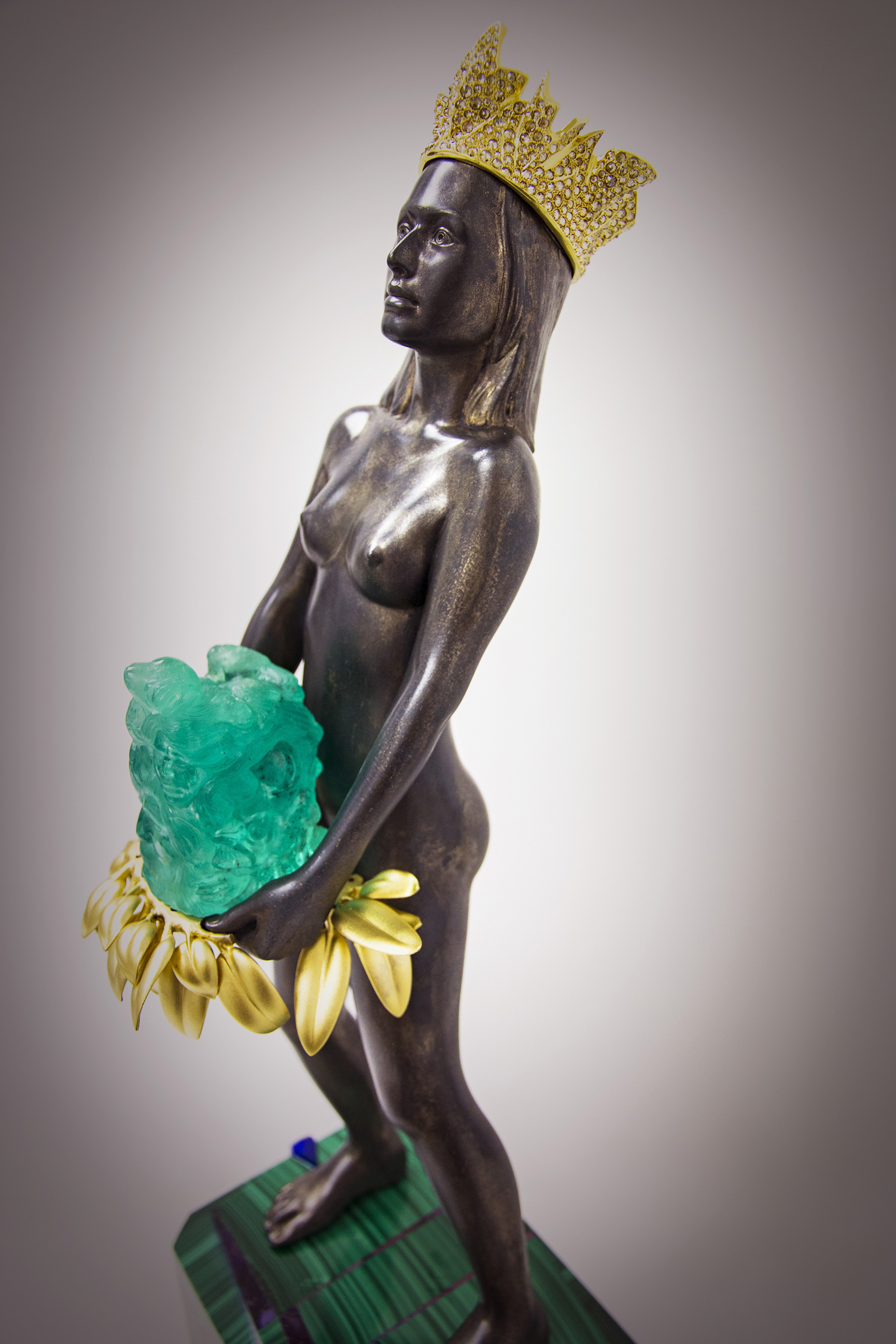  The emerald carving's final weight is 1,550 carats featuring nine images that reference the 500th Anniversary of &nbsp;the European arrival in the Americas. Total approximate height of the statue including feet on base to top of crown is 63.6 cm (25