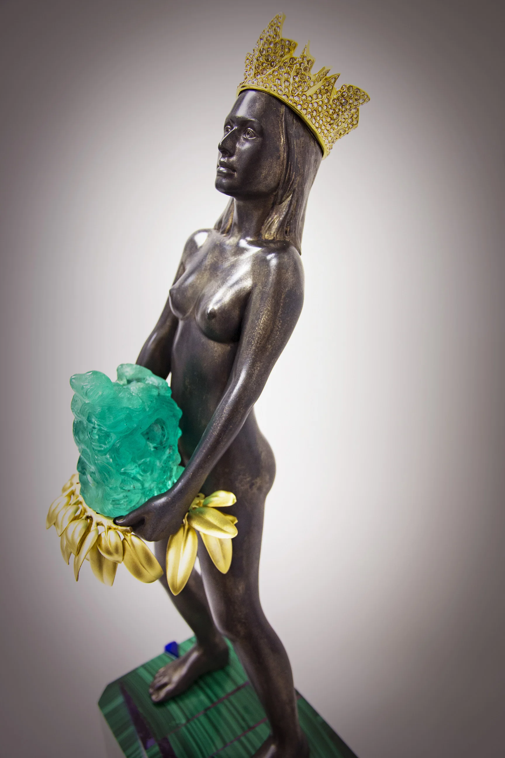 The emerald carving's final weight is 1,550 carats featuring nine images that reference the 500th Anniversary of the European arrival in the Americas. Total approximate height of the statue including feet on base to top of crown is 63.6 cm (25"). For more information regarding price and availability, please contact: info@thomasrmcpheesculptor.net