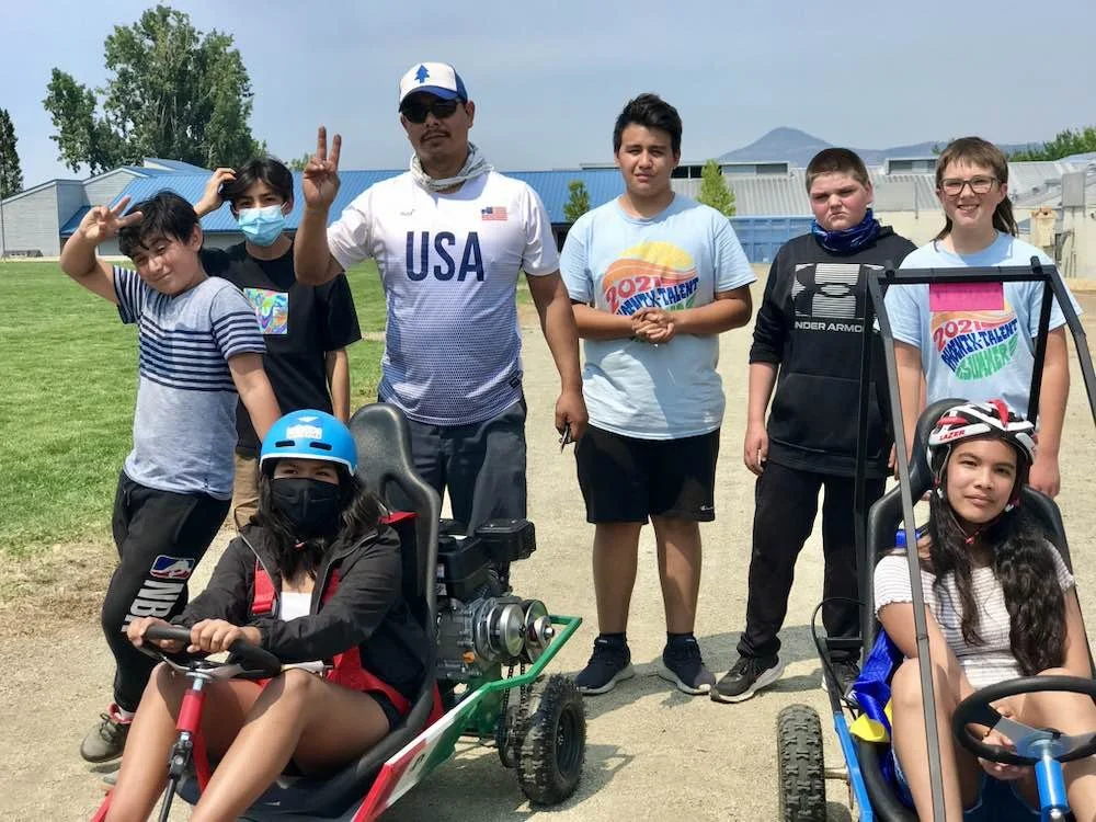 Two students in go-karts with other behind them.