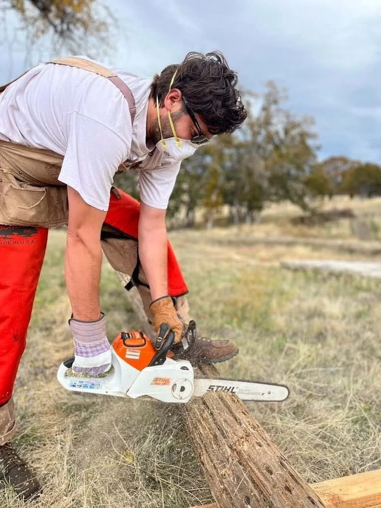person chainsawing telephone pole