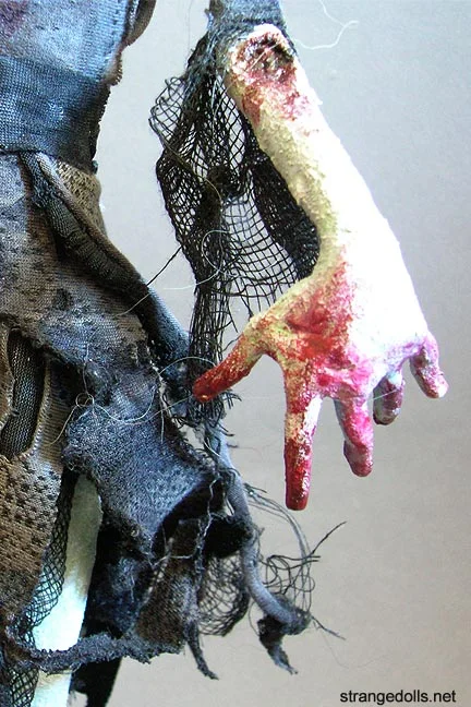 This Zombie Girl stands 19" tall. She is a hand made sculpture. She was sculpted from Aves Apoxie Sculpt and painted with acrylic paint. Her clothing was fashioned on to her body and sewn. She is affixed to a wood base.