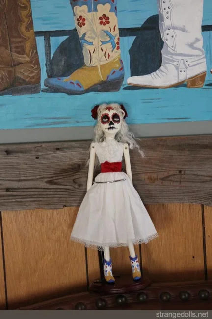 This customer is from New Mexico, where Day of the Dead traditions are still celebrated in the US. She commissioned me to make the doll wearing her favorite custom cowgirl boots. There is a painting of the boots in this photo behind the doll.