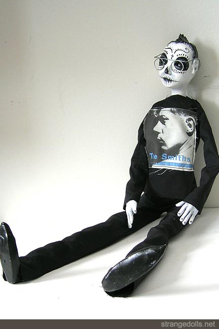 The doll is 22" tall. It was hand sculpted using air dry clays Paperclay and Apoxie Sculpt. The clothing is hand sewn (the Smiths album cover a photo transfer onto fabric). The spectacles are fashioned from wire. His body is made using a wire armature so he can sit and stand with ease. He was made in 2010.