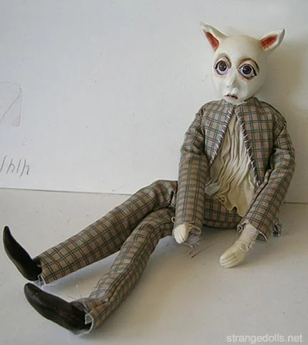 This somber little guy is wearing a plaid suit with an ecru ruched shirt. His body is a wire armature so that he can sit or stand.
