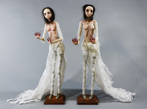 They are 18.5 inches tall sculptures that are mounted to a wood base. They are hand sculpted using a mix of polymer clays that, when cured, have a very lifelike, pristine quality. Their clothing is white velveteen and 100% cotton to represent their innocence. They are topped with real human hair. They have metal hooks in their back and their hands are pulling them out with fishing line as they look forward with eyes filled with disillusionment and acceptance of the process.