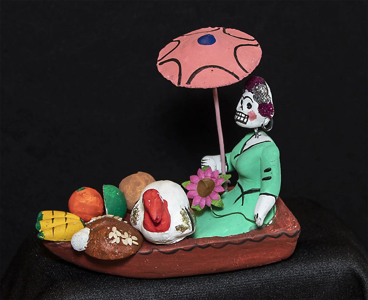 These little figures are made to decorate altars and as toys for children. A Day of the Dead figure in a boat filled with corn, pan de muertos and a turkey.