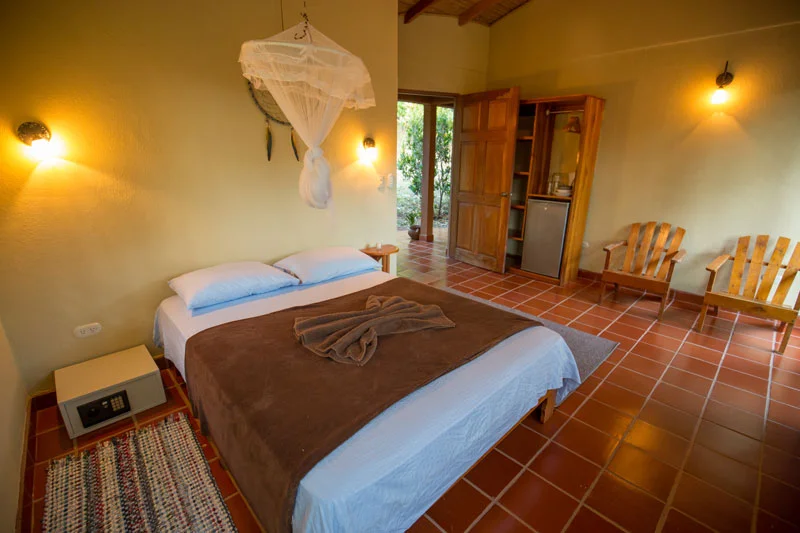 The AC Rooms are an air-conditioned, peaceful and private option for those seeking more of the comforts of home. They include one large bedroom with a queen-sized bed and mosquito net, a balcony sitting area, and a small refrigerator. Each cottage has a private bathroom with hot shower. These 20 square meter rooms can be closed completely with sliding doors, window screens, and shades, and a ceiling fan directly over the bed keeps things cooler. Located right by the Internet Cafe, the cottages are five minutes walking distance from the village center. AC Room Package: Early Bird $1170 / Regular $1200 Shared AC Room: Early Bird $1970 / Regular $2030